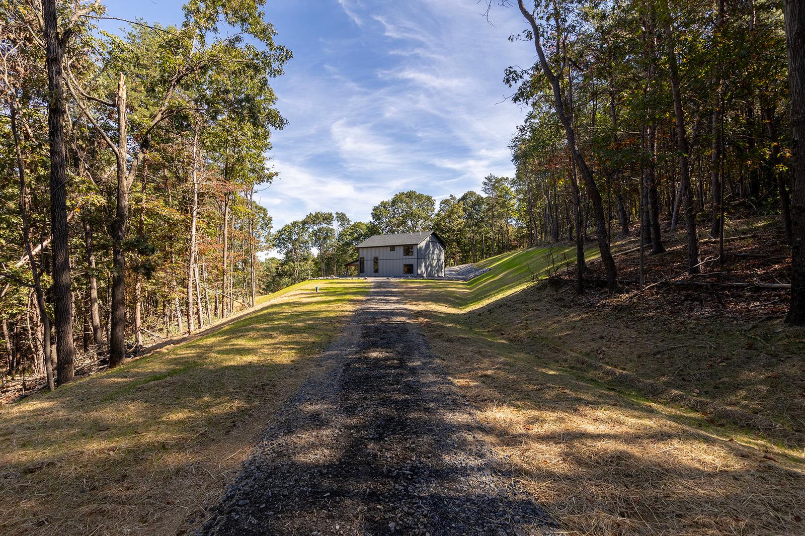 Long gravel drive climbing through the trees to the home on the hilltop, woods close on both sides