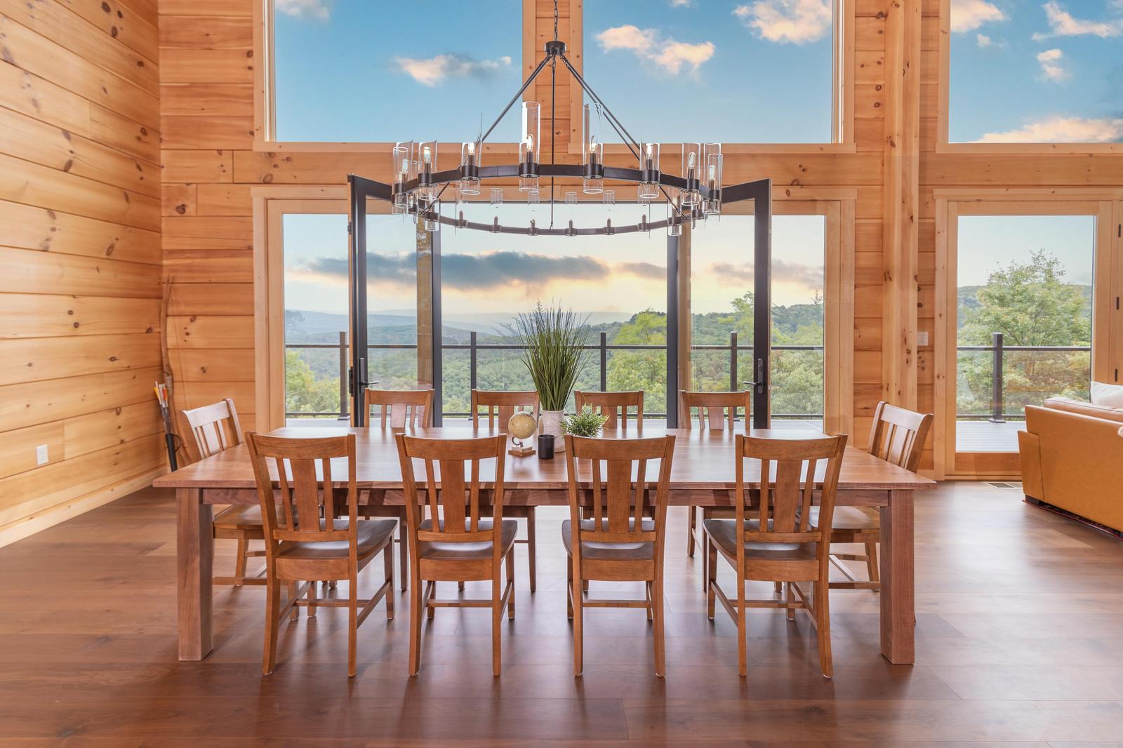 Dining room with timber beam ceiling, iron chandelier, large windows with mountain views