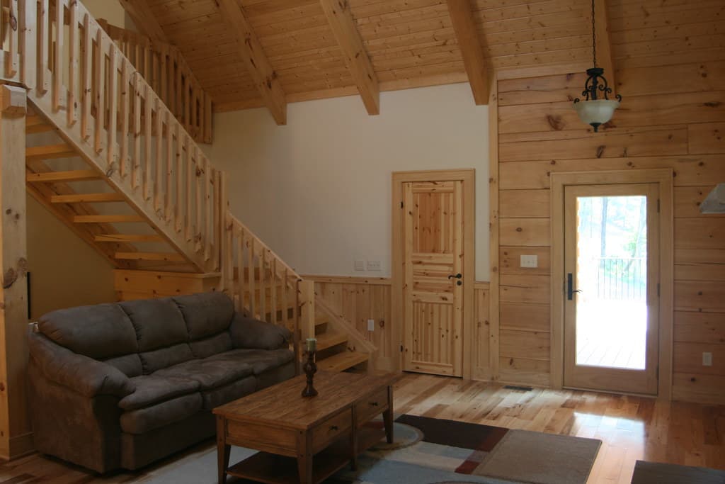 The living area with the open stair behind it, the front door and its glass panel throwing light across the floor