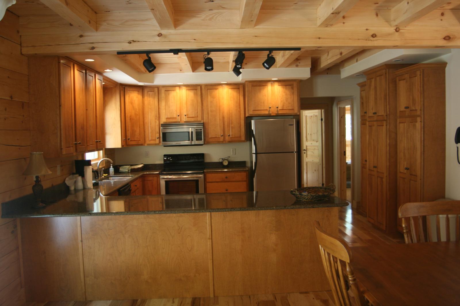The kitchen from the dining end, a long counter dividing the two and beams running across the ceiling