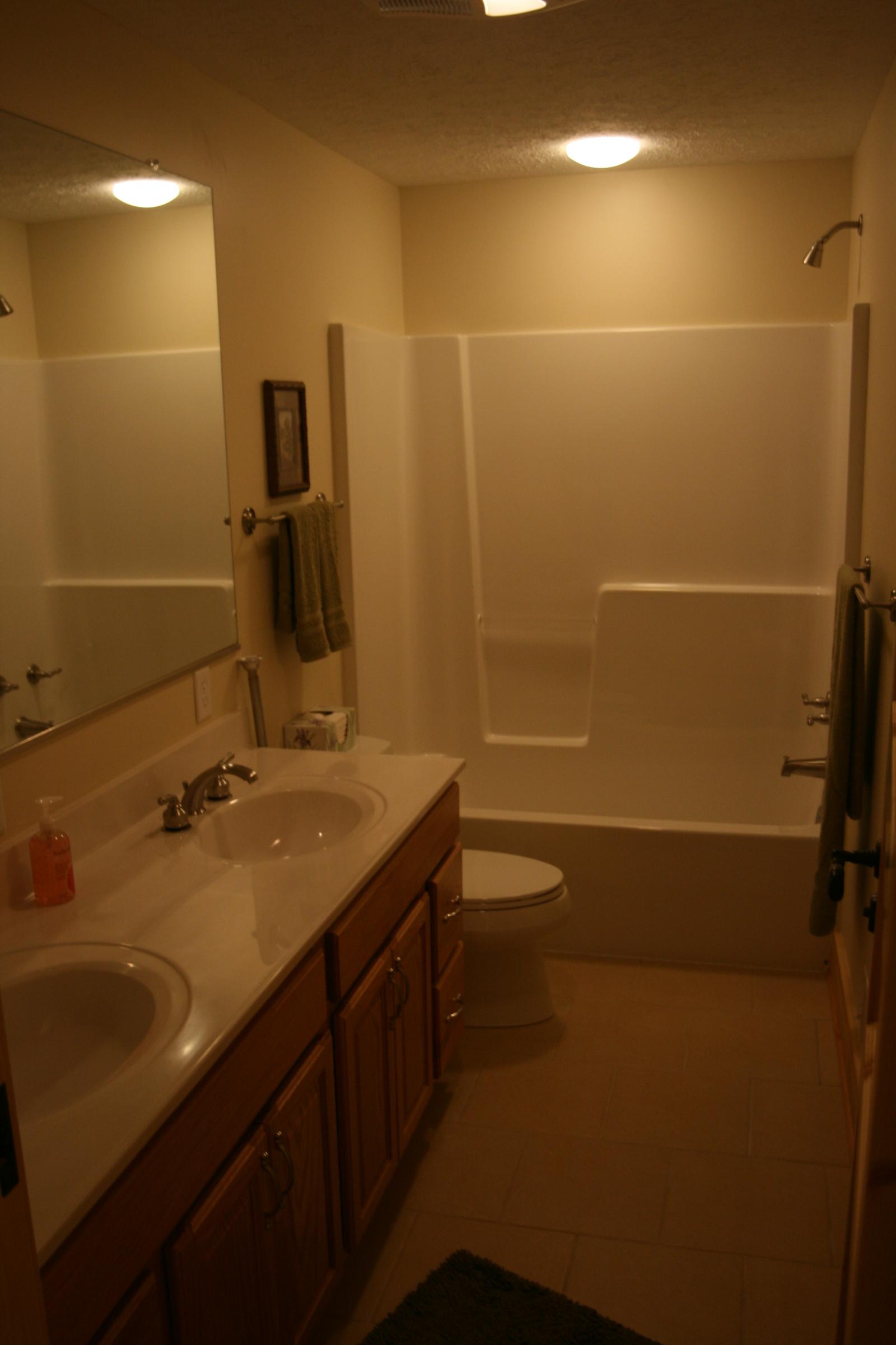A bathroom with twin basins in a long counter and a tub and shower beyond