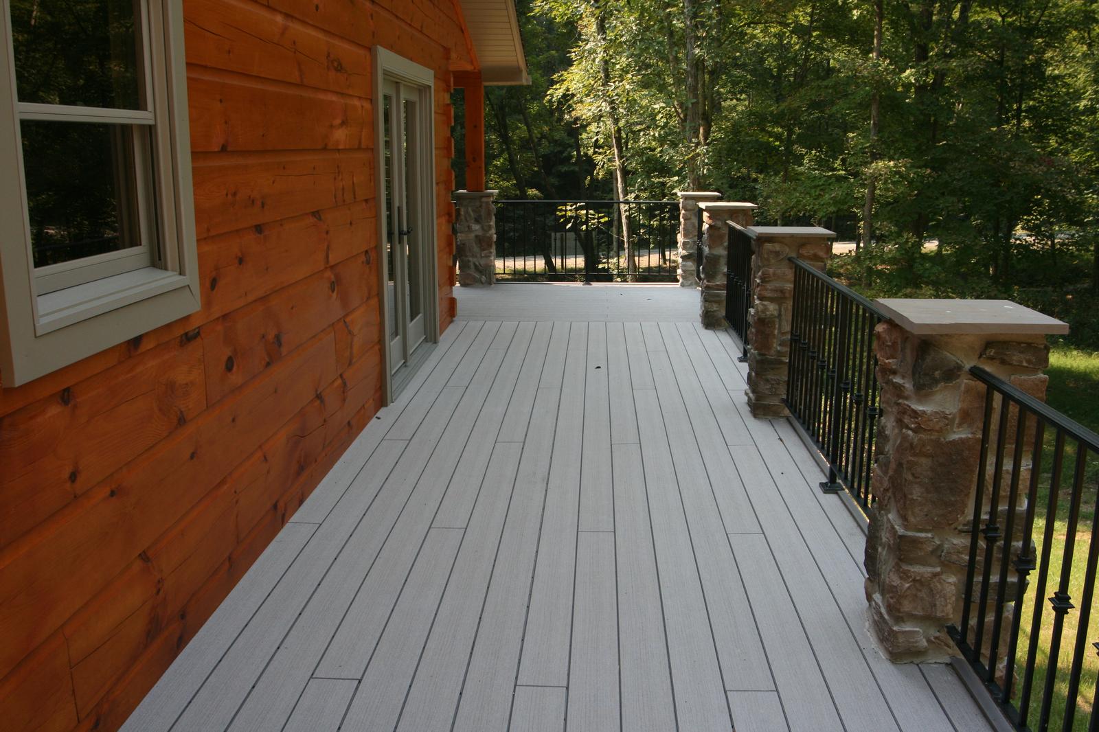 A deck running between the log wall and a black railing, doors opening off it