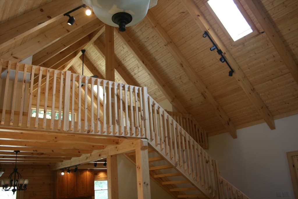 The loft rail and open stair against the cathedral ceiling, a skylight set into the boarded slope