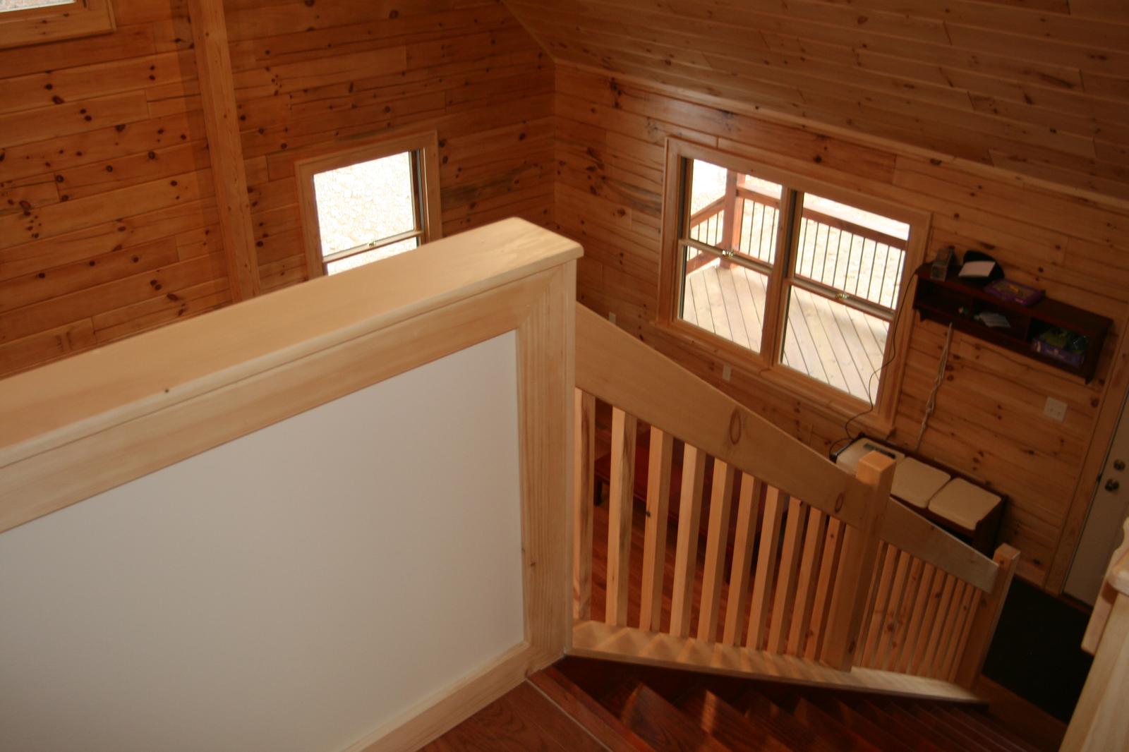 The loft rail looking down, board walls and a window throwing light across the floor