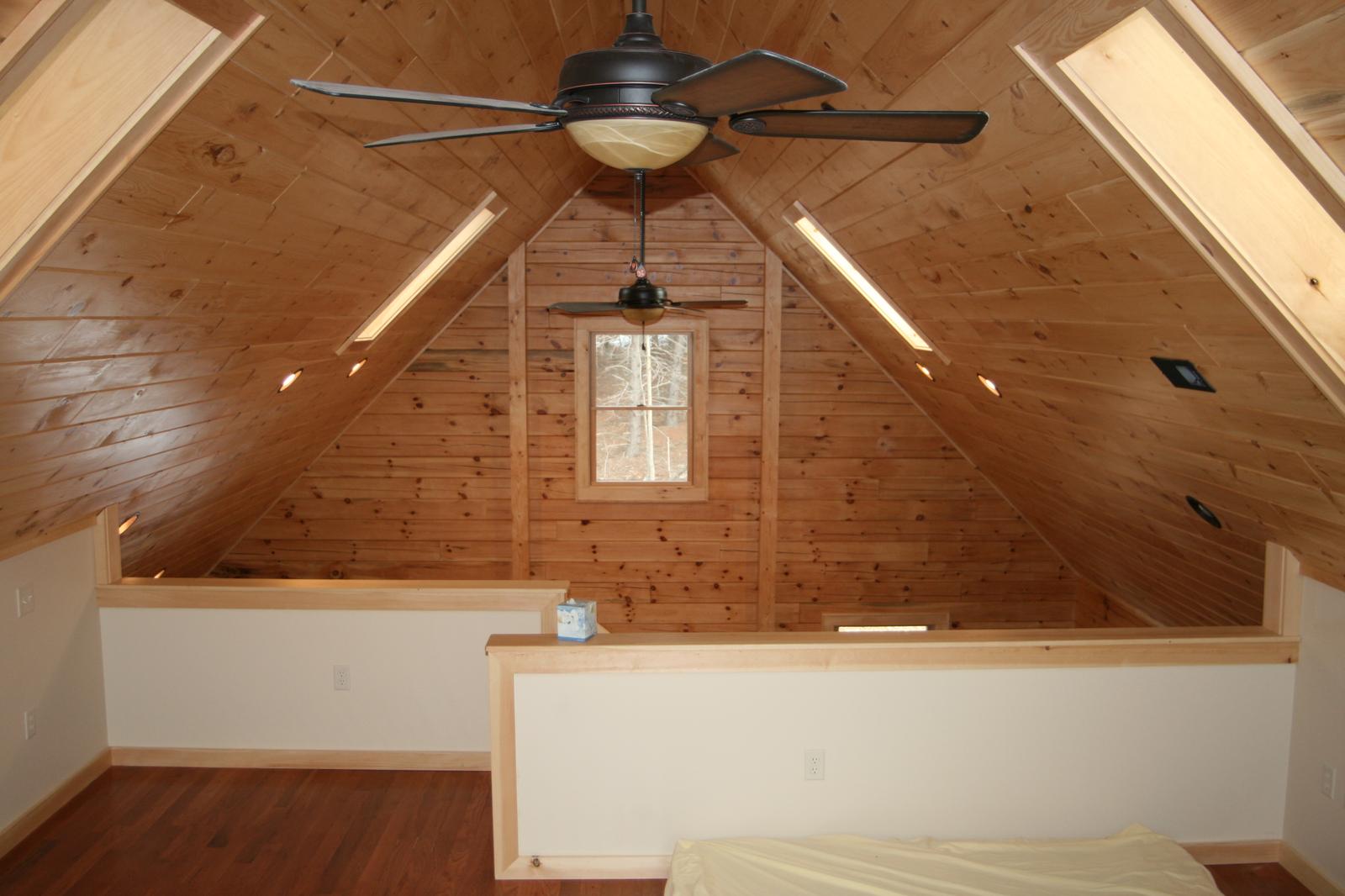 A loft bed under the slope, knee-walls either side and a small window centered in the gable