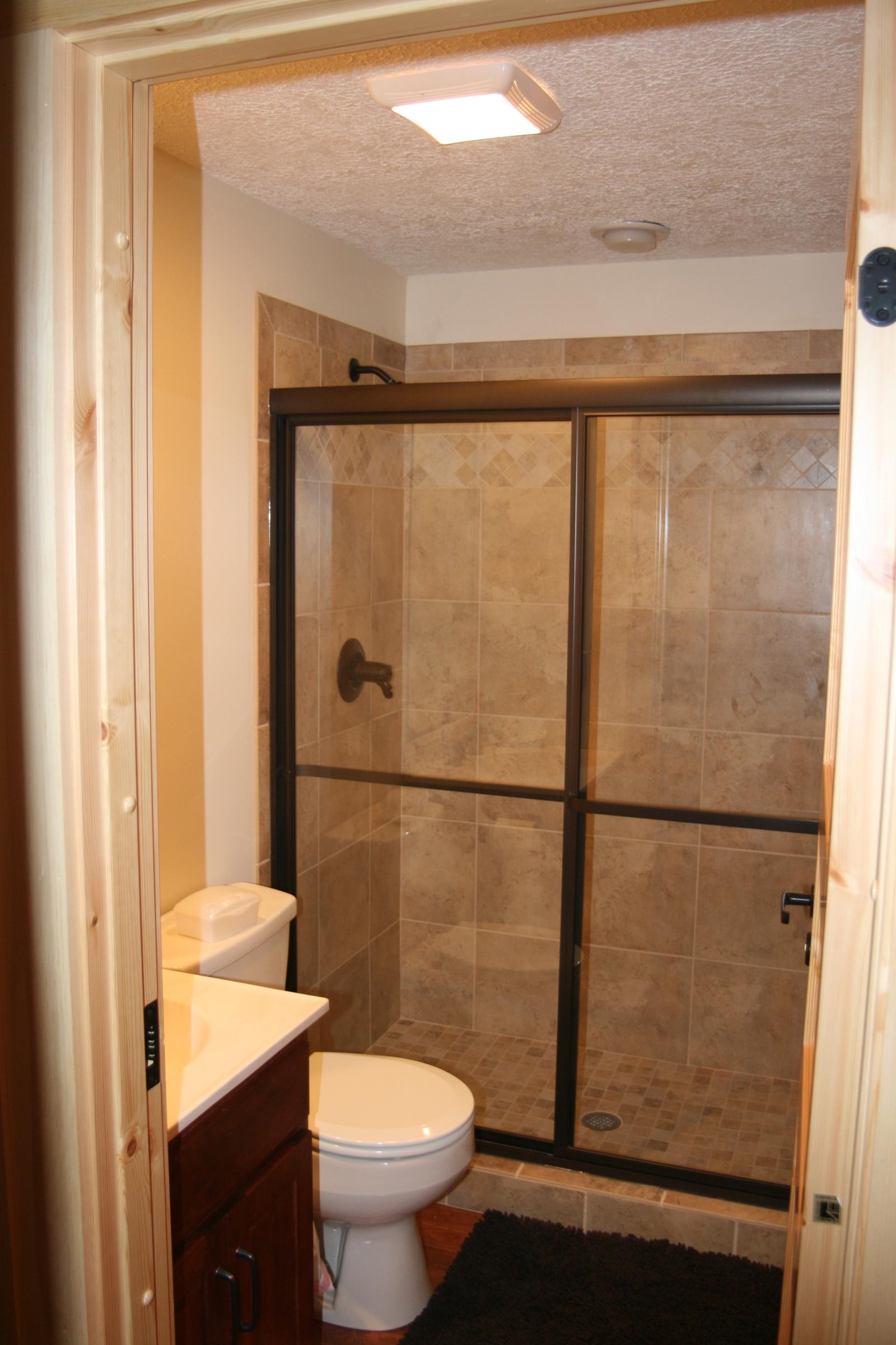 A bathroom with a sliding glass shower door, a vanity beside it and a tiled floor