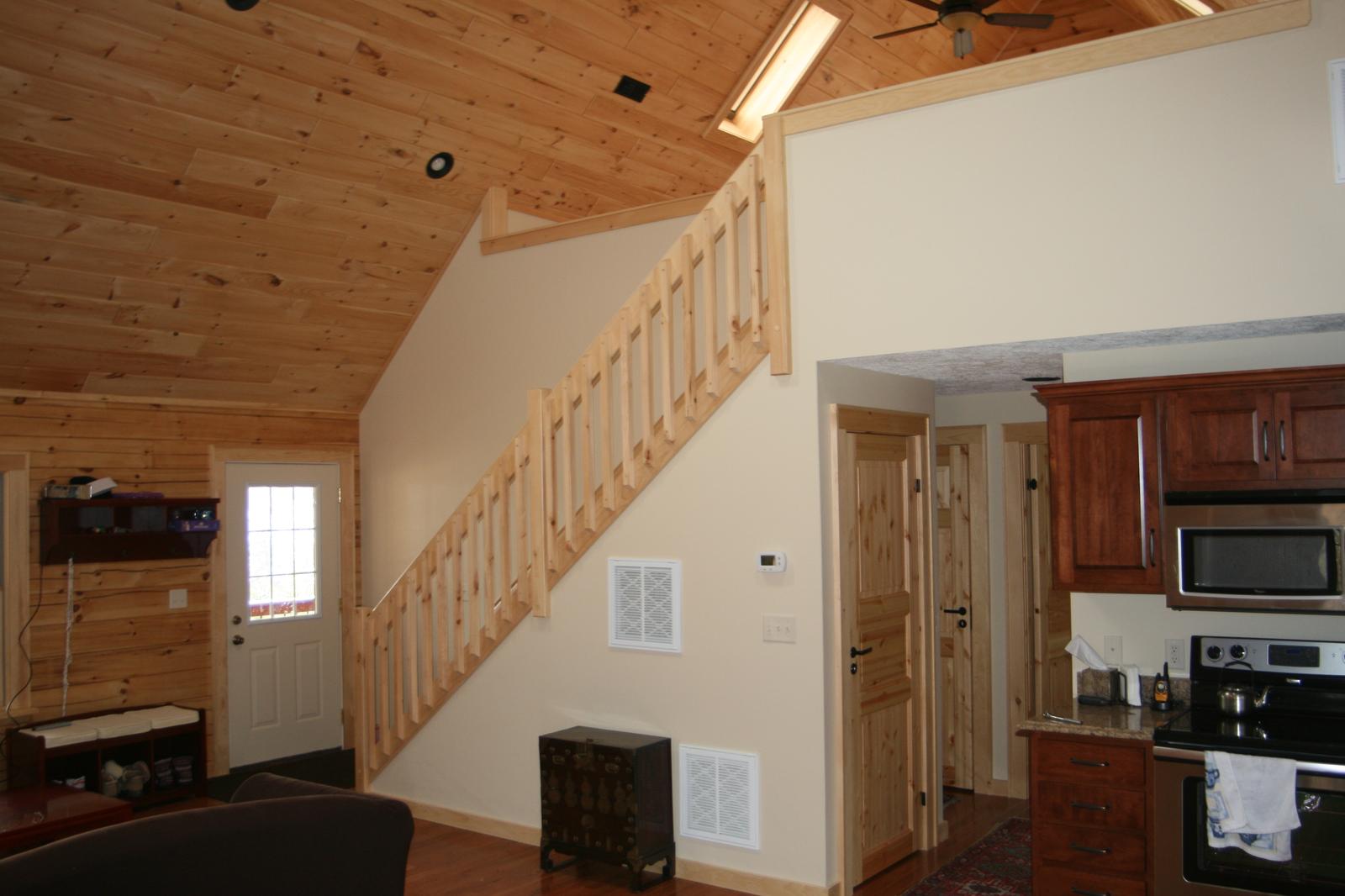 An entry with a stair rising beside it, a kitchen visible through the opening beyond