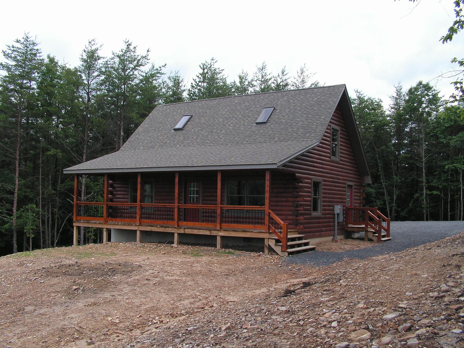 The home from the open ground, porch across the front and bare earth graded around it