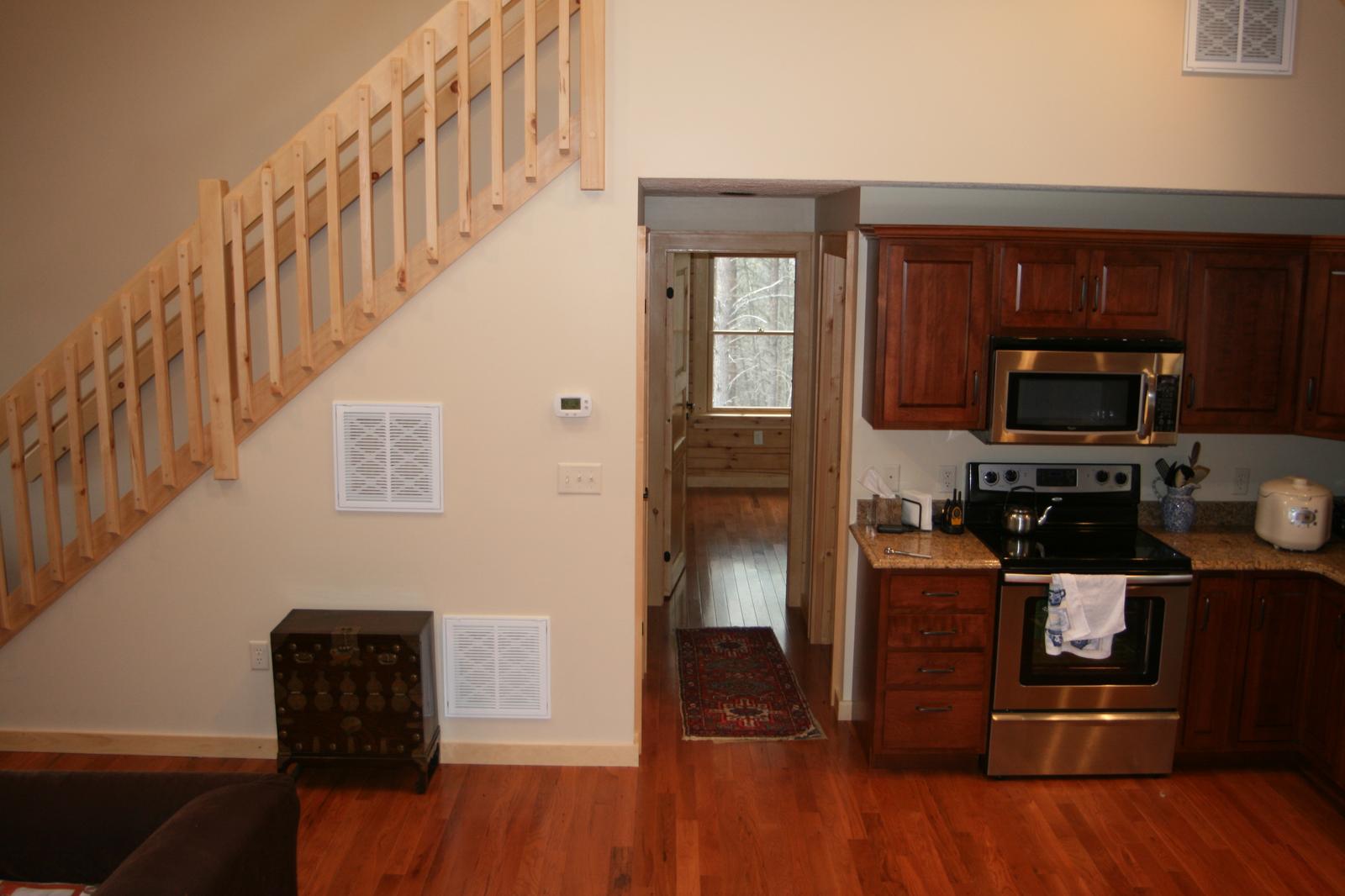 The kitchen from the stair, a range and refrigerator beyond an open door to the porch