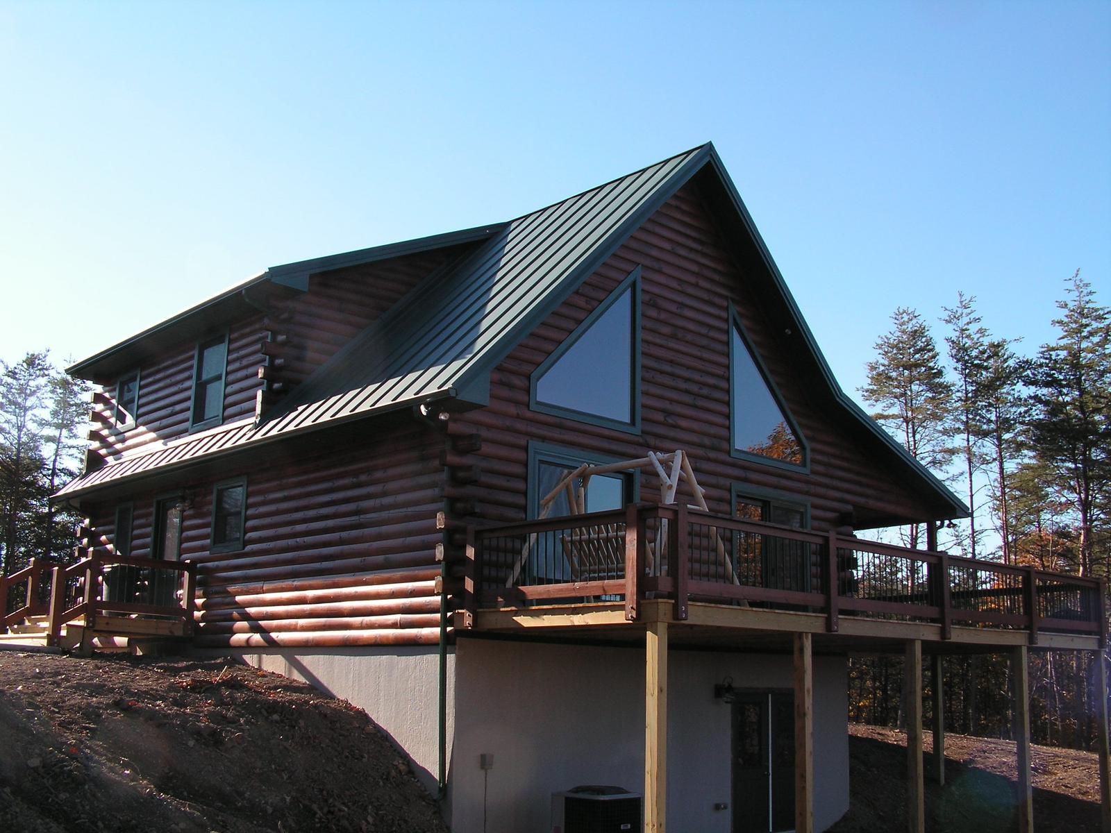 The home from below, gable of glass above a railed deck standing on posts