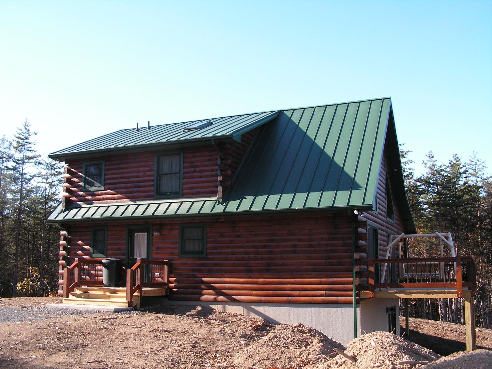 The home from the drive in low sun, deck steps at the near end and bare ground around