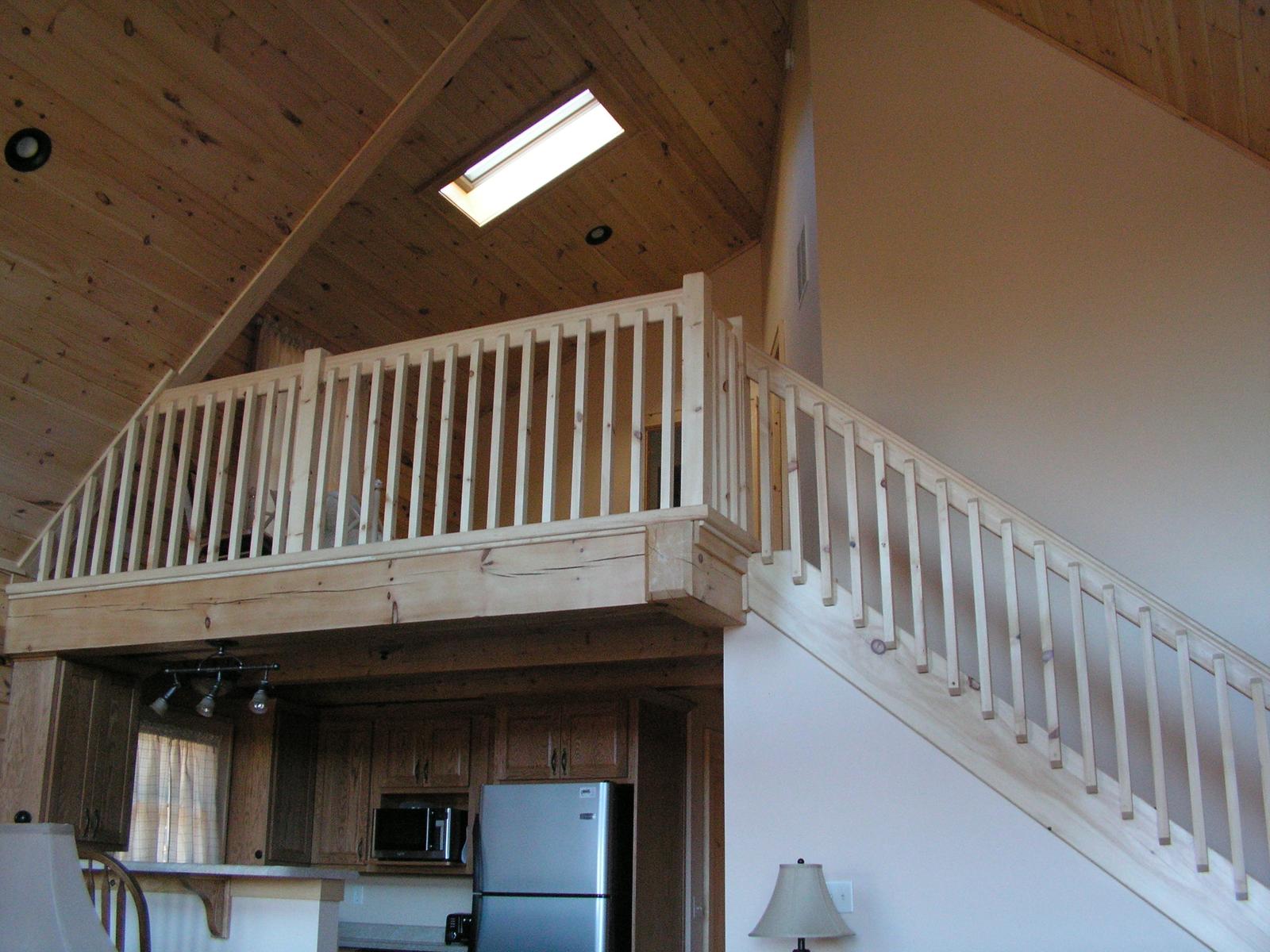 A loft rail under a skylight, the kitchen visible below through the opening