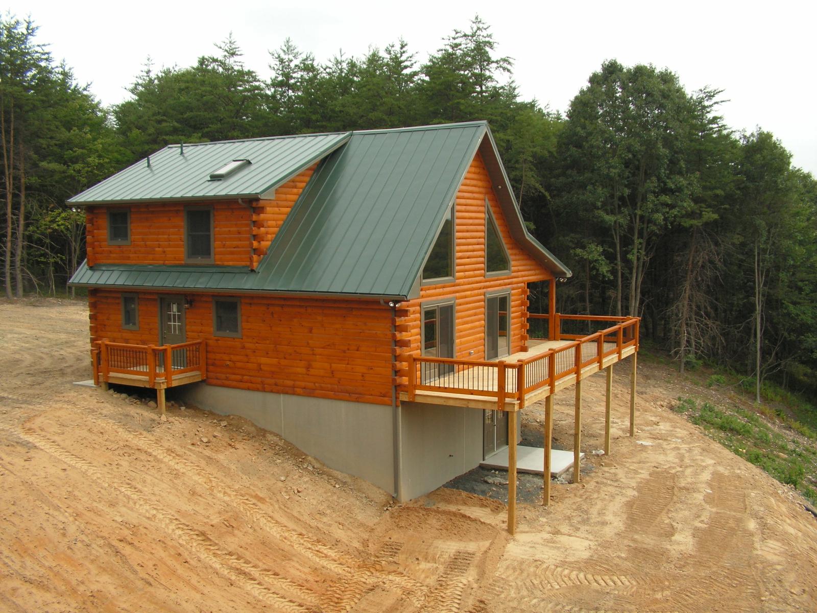 The home from the side, deck and rail along the walkout level and raw earth graded around