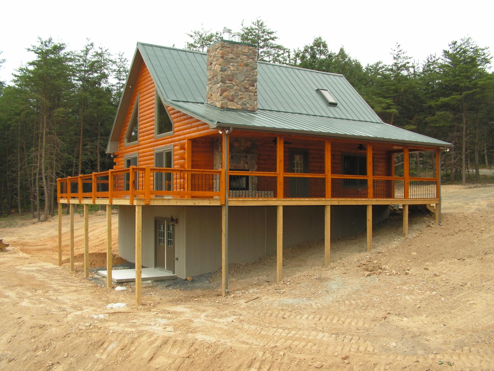 The home from the low side, a stone chimney at the ridge and the deck carried on posts