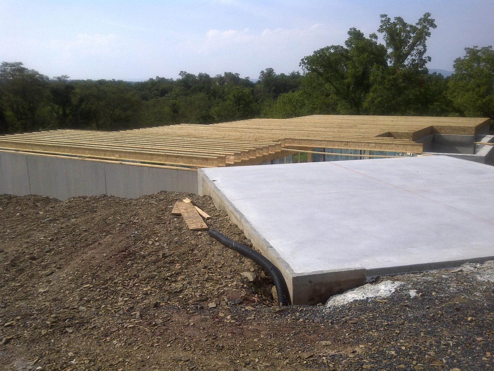 The subfloor decked over the foundation, a concrete slab poured alongside, spoil banked around the edges