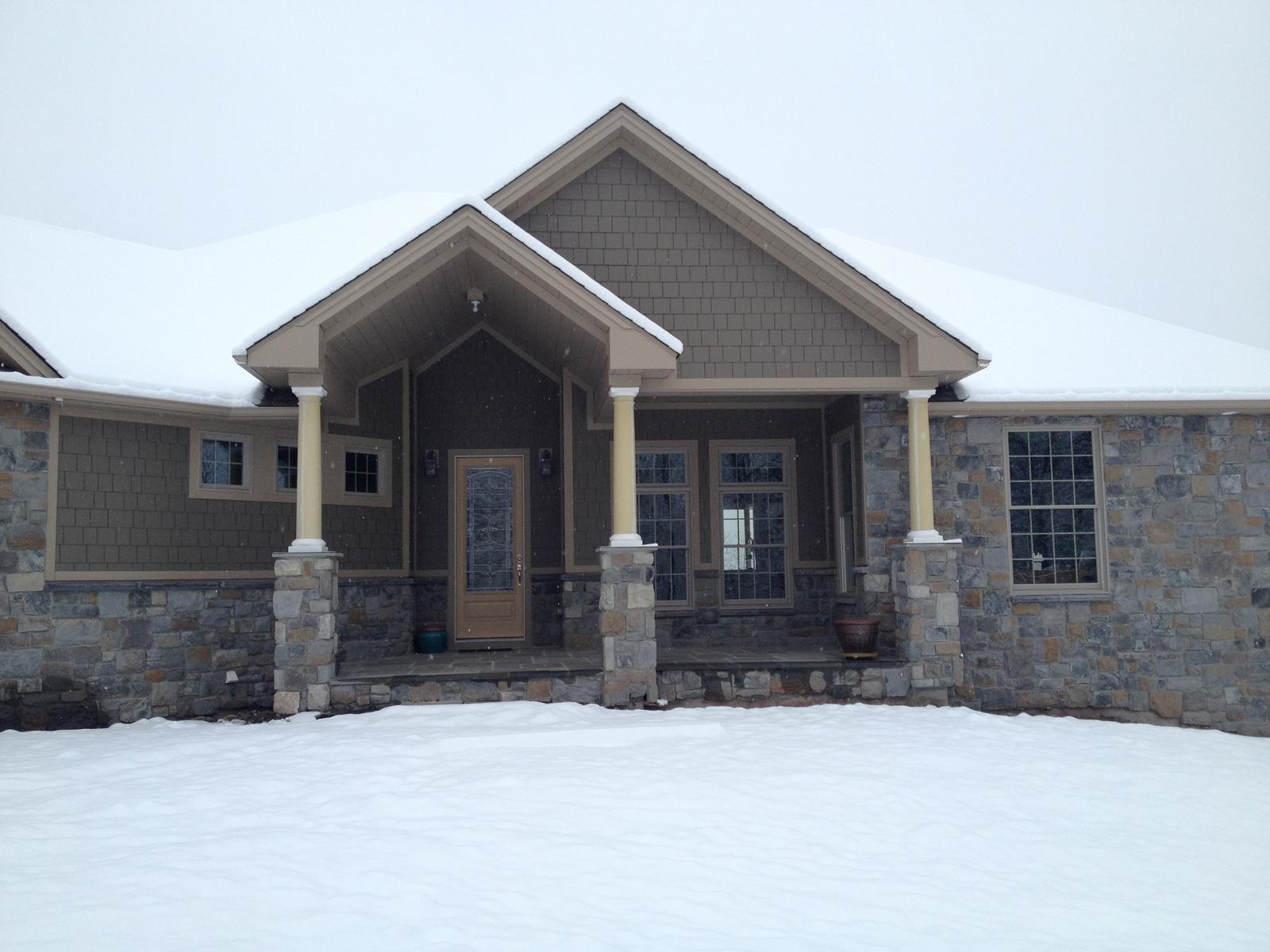 The entry porch straight on in deep snow, both columns and the paneled door centered under the gable
