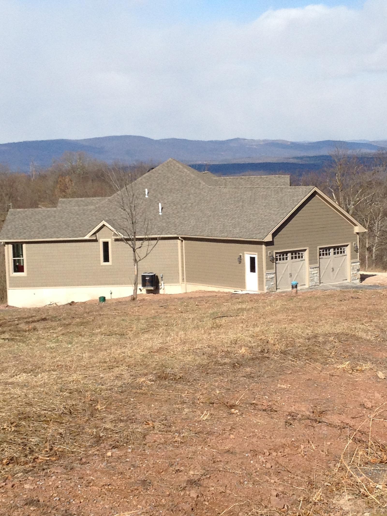 The house and garage wing seen along the slope, mountains ranged along the horizon behind
