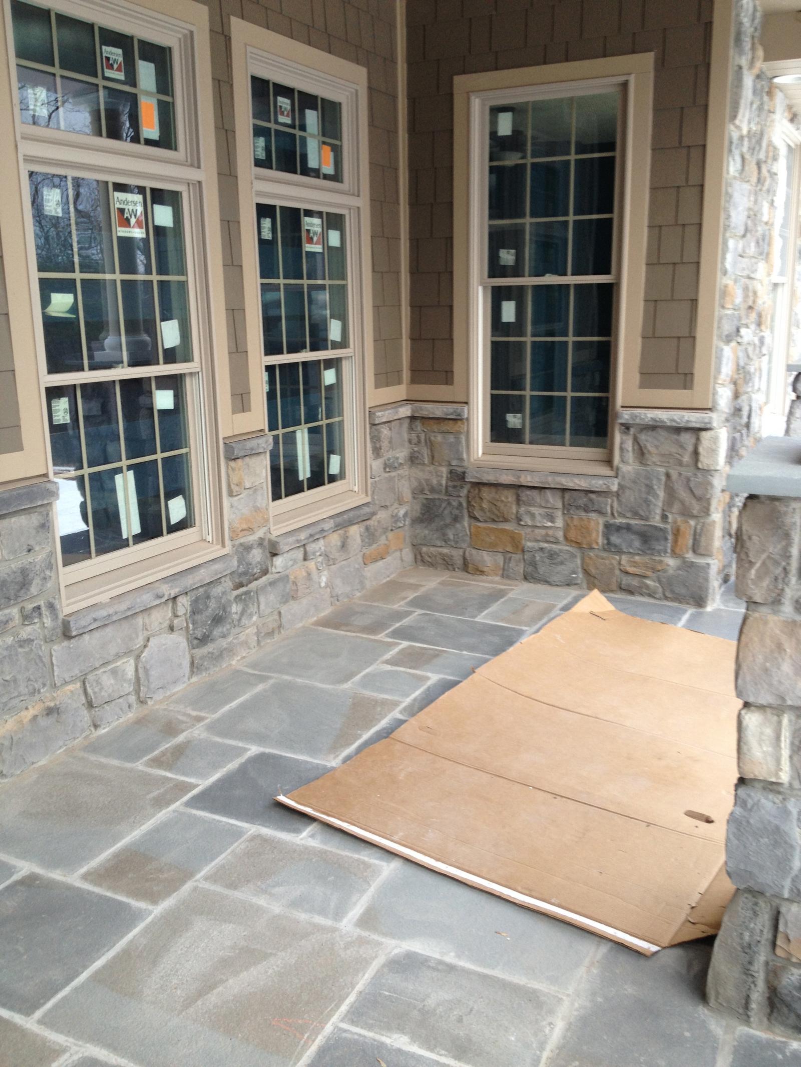 The porch and its flagstone floor, window stickers still on the glass and a sheet of underlayment laid down