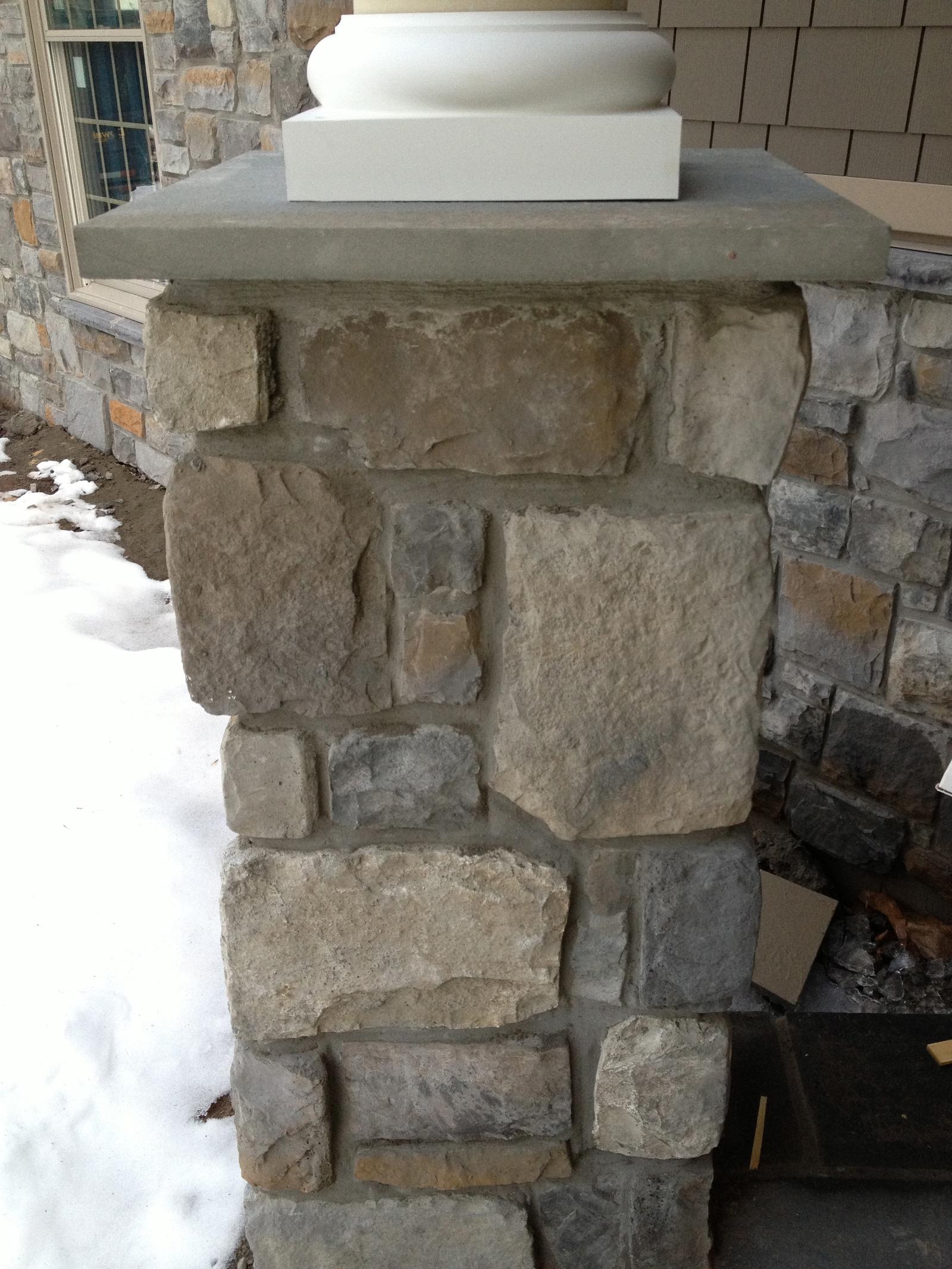 A porch pier close to, its cut stone capped with a slab and the column base set on top