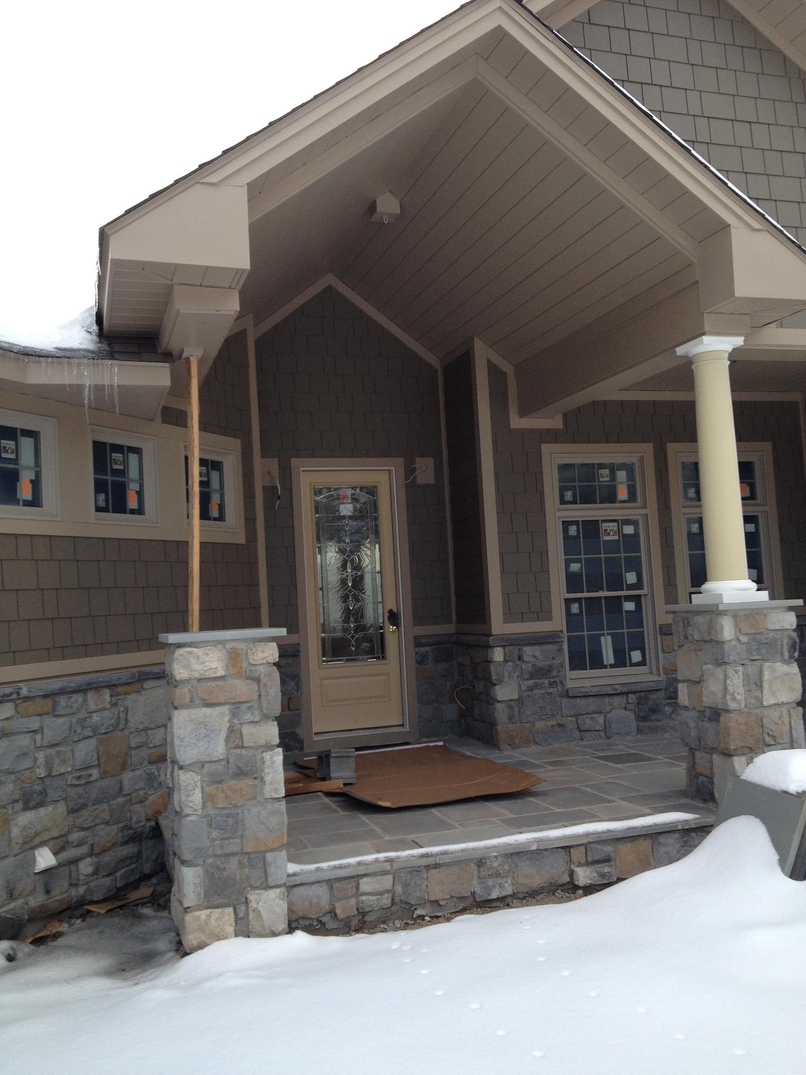 The front door and porch from the walk, snow banked either side of the step