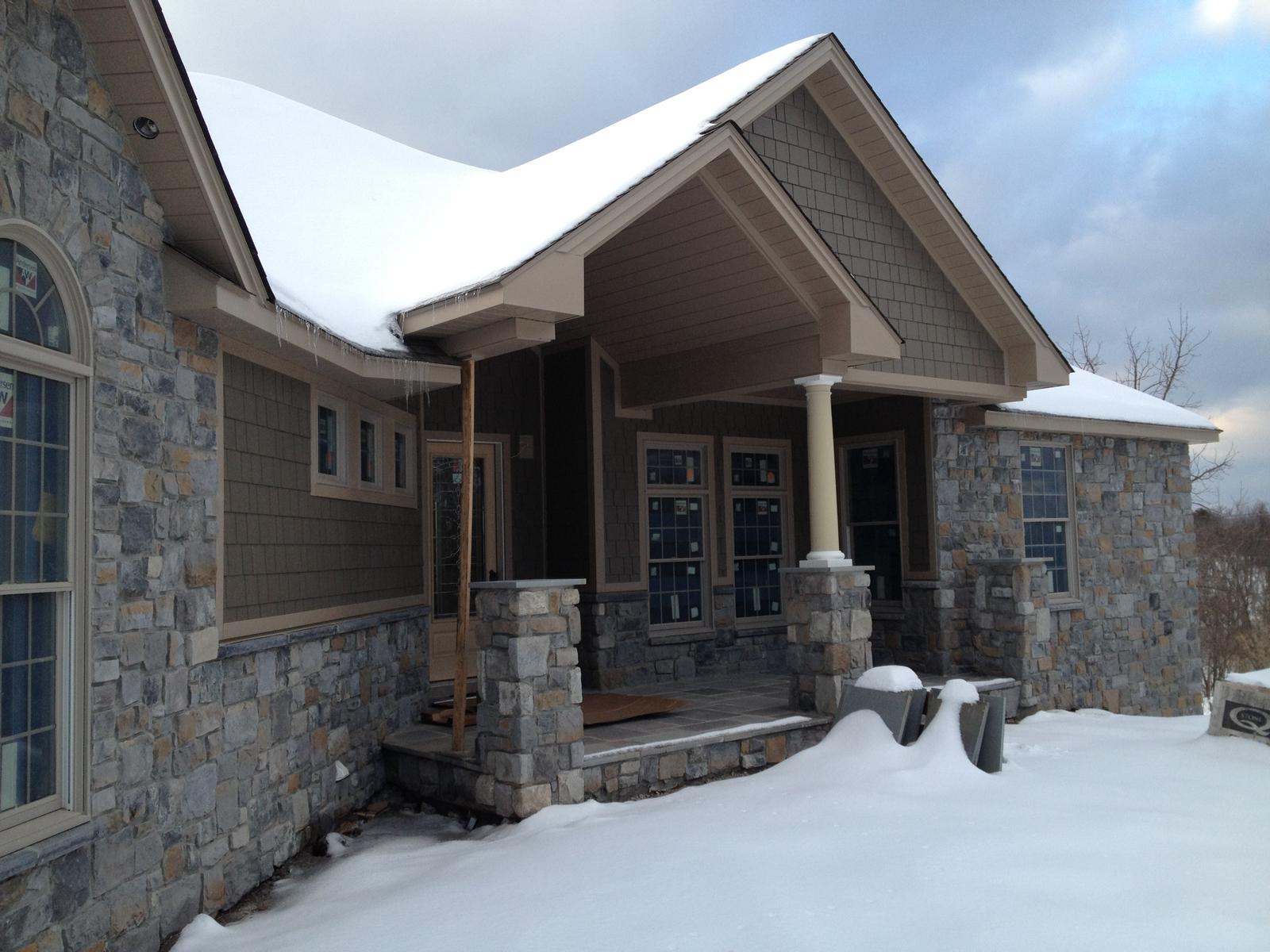 The entry porch under snow, stone piers and columns framing the door
