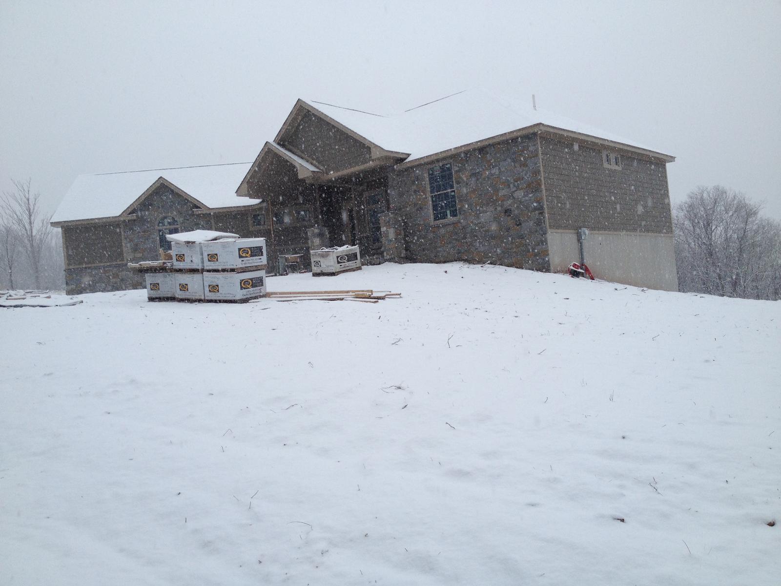The house across snow-covered ground, both gables and the garage wing under one roofline