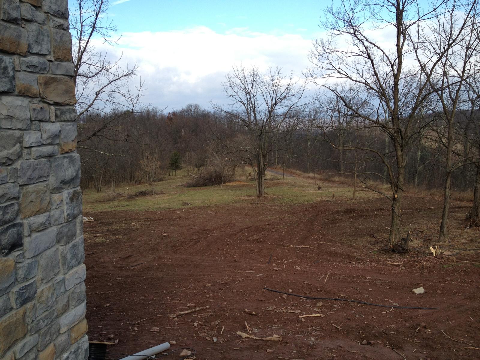 The view out past a stone corner of the house, mown ground falling to bare woods and mountains beyond