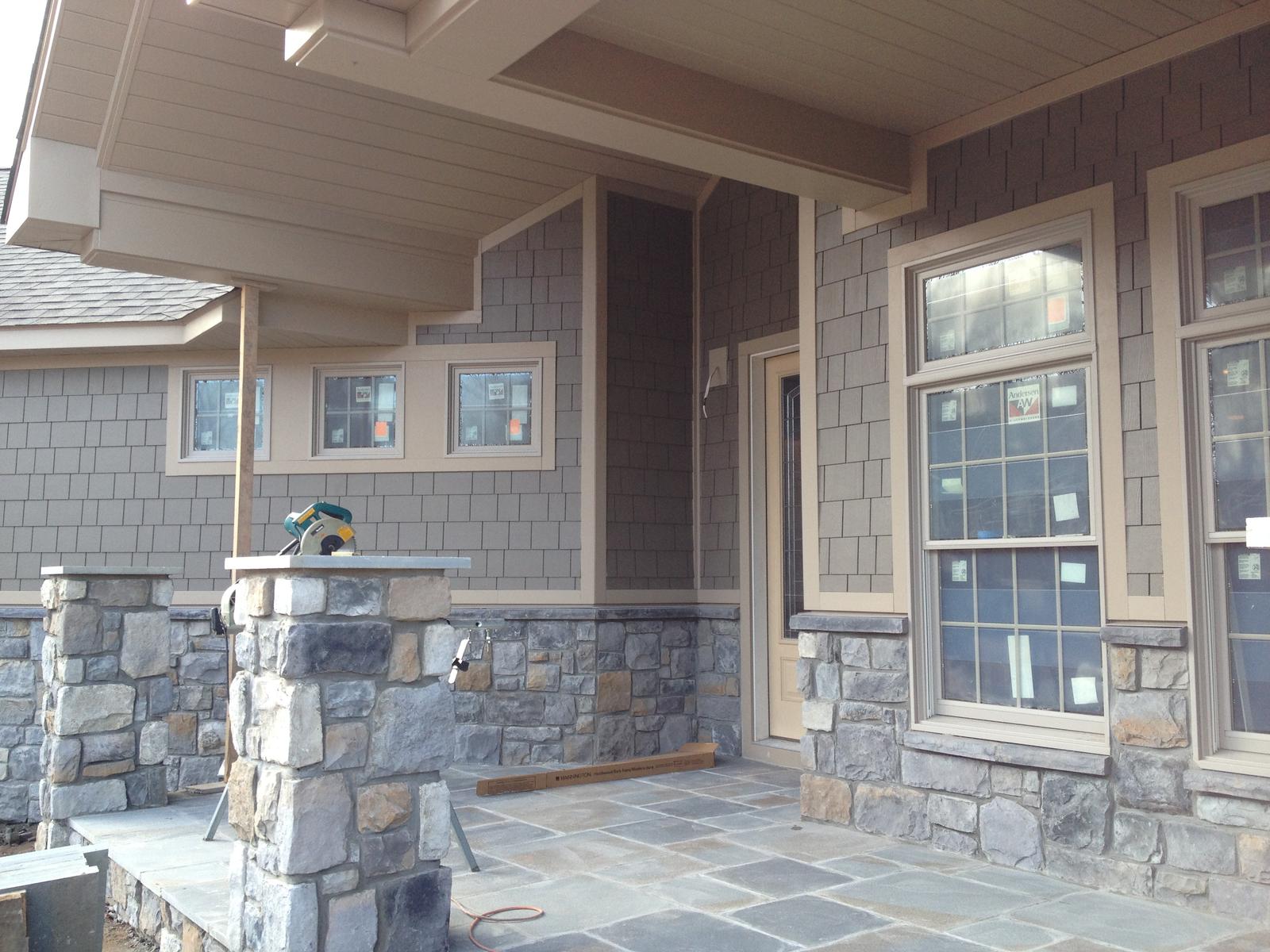 The porch mid-build, stone piers up and a column set, flagstone laid in part across the deck