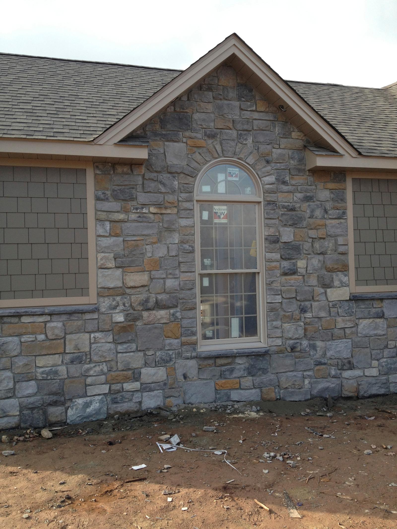 A stone gable end with an arched window, the stonework run right up under the eaves