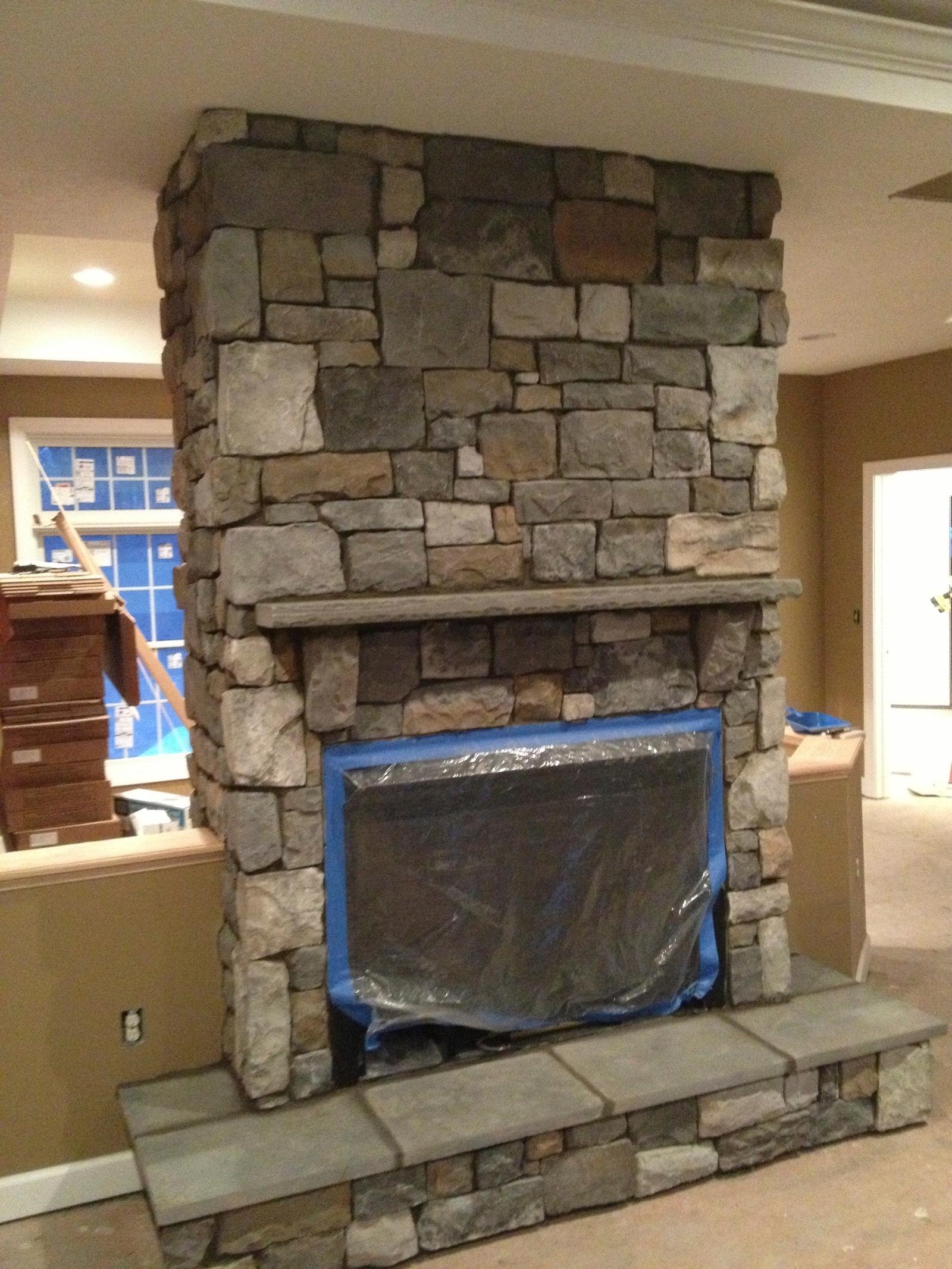 The fireplace part built, stone laid to the ceiling and the firebox opening still masked with plastic
