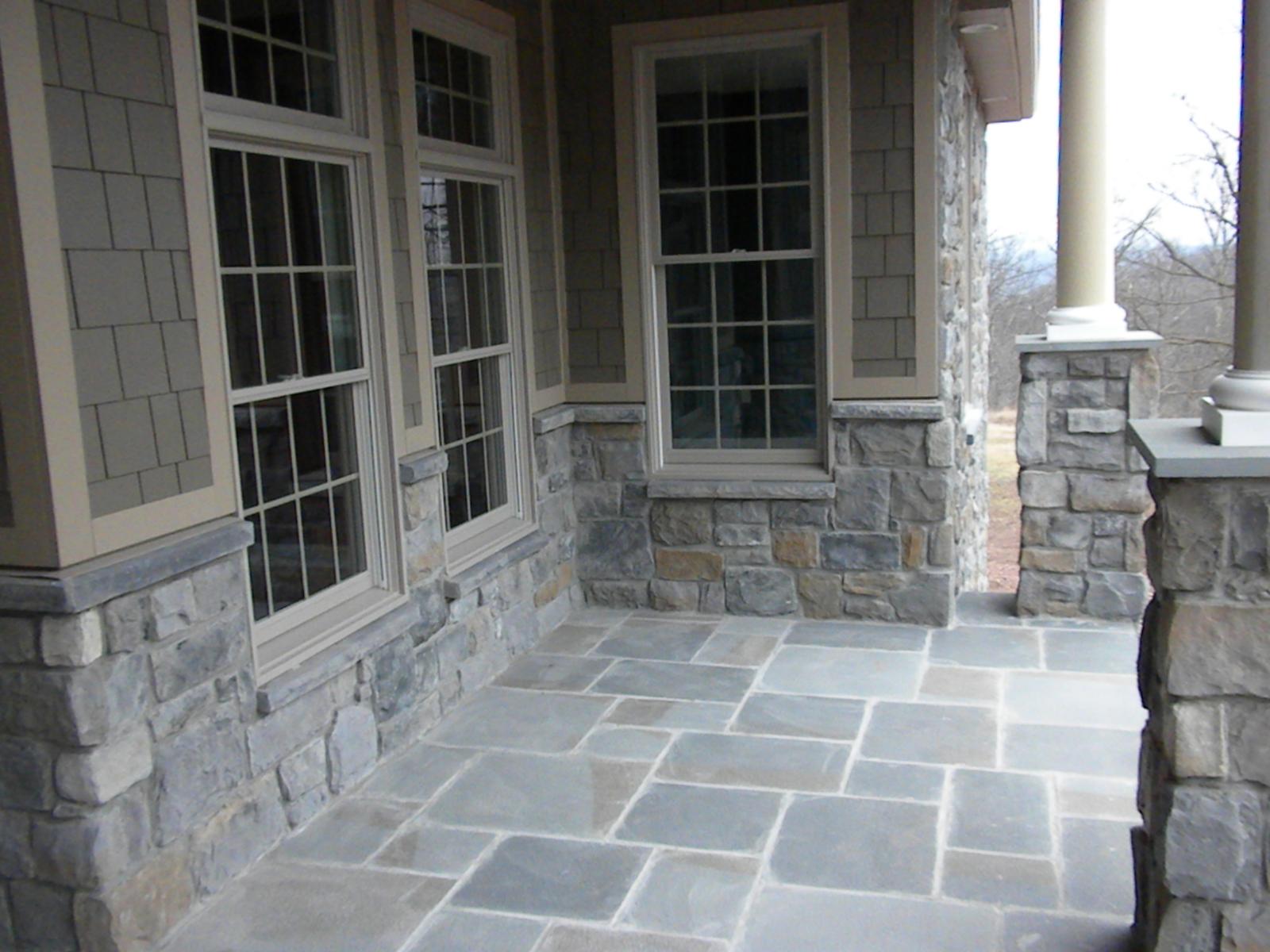 The porch from the far end, flagstone paving and a column base, windows running the length of the wall