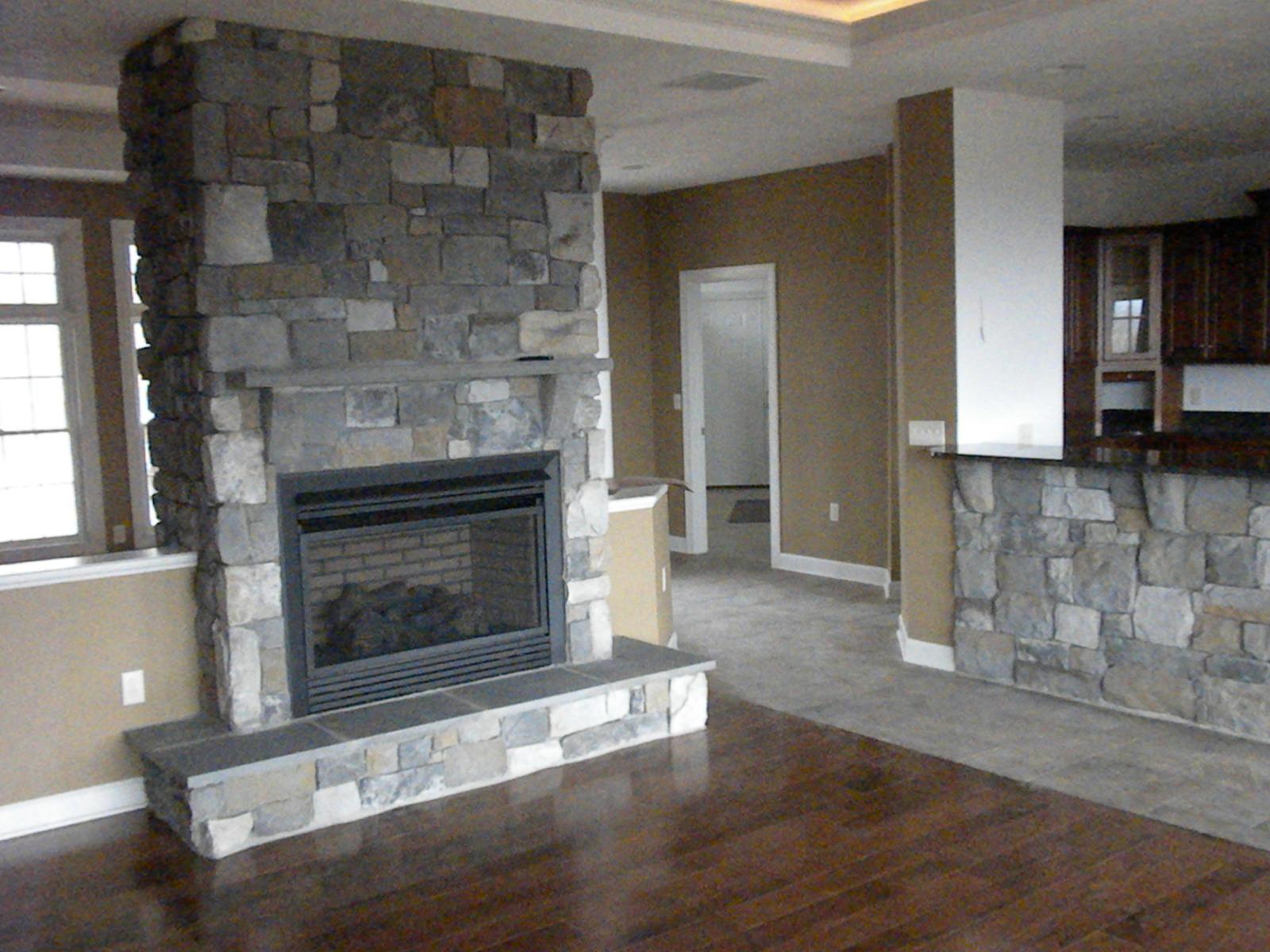 The great room from the hearth, stone chimney and a stone-faced counter dividing it from the kitchen