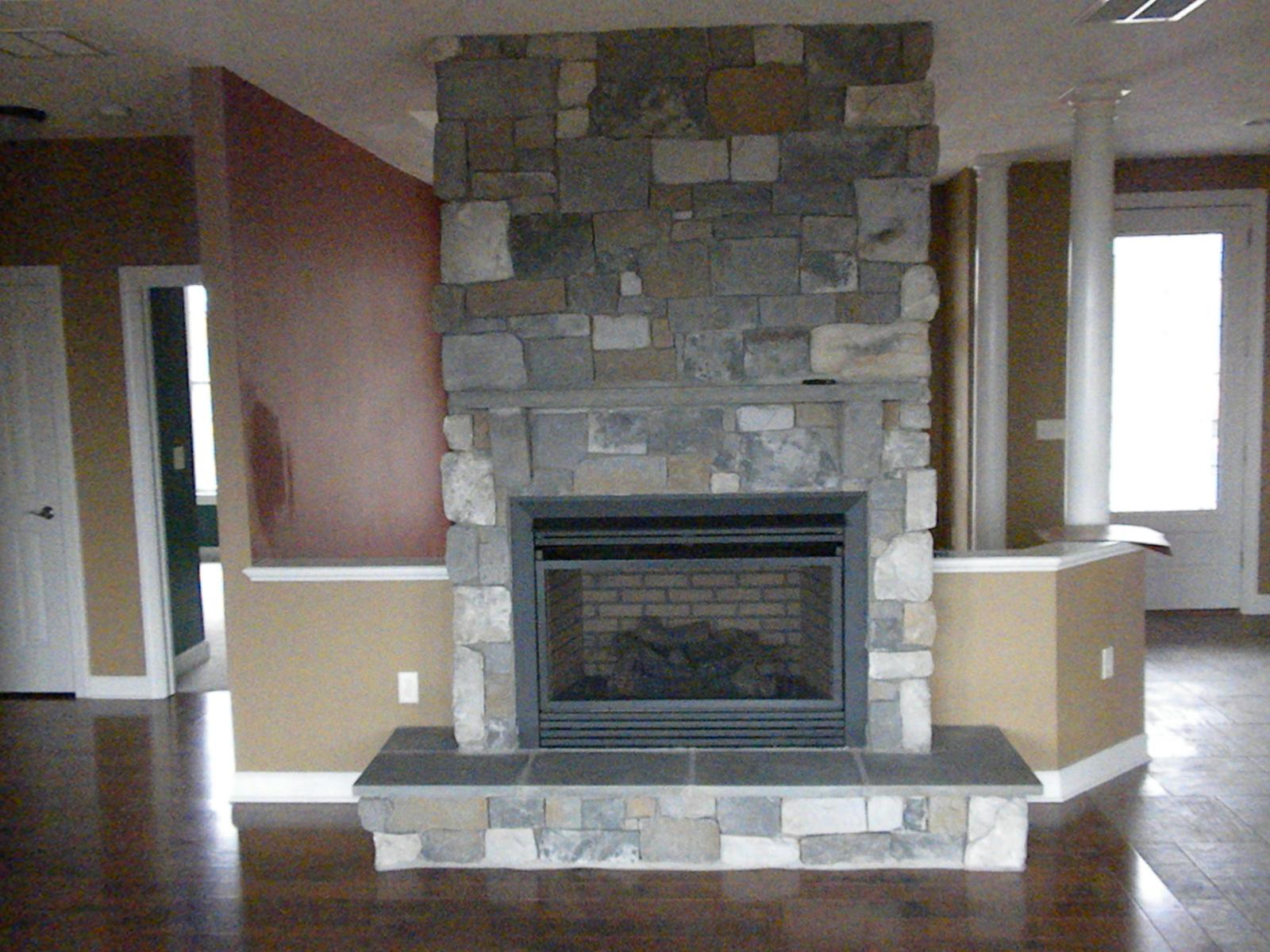A stone fireplace with a raised hearth built out into the room, red and tan walls either side and a glazed door beyond