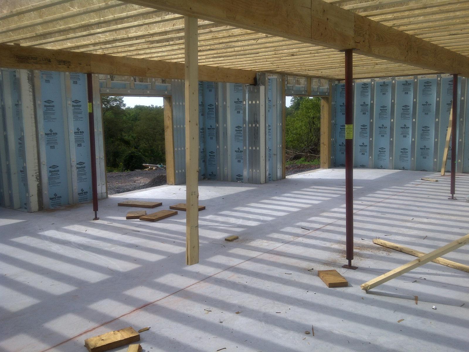 The basement looking toward two window openings, timber posts and steel columns under the floor above