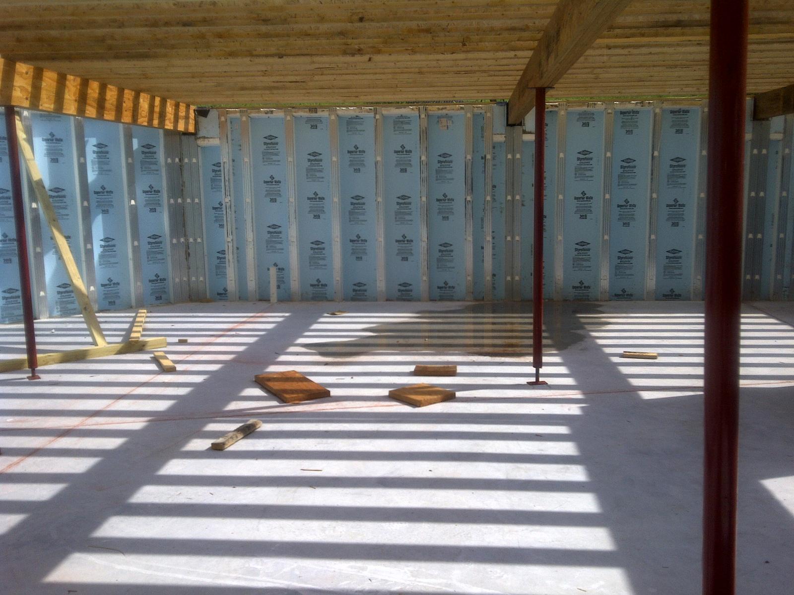 The basement from inside, insulated foundation panels on every wall and steel columns carrying the floor beams overhead