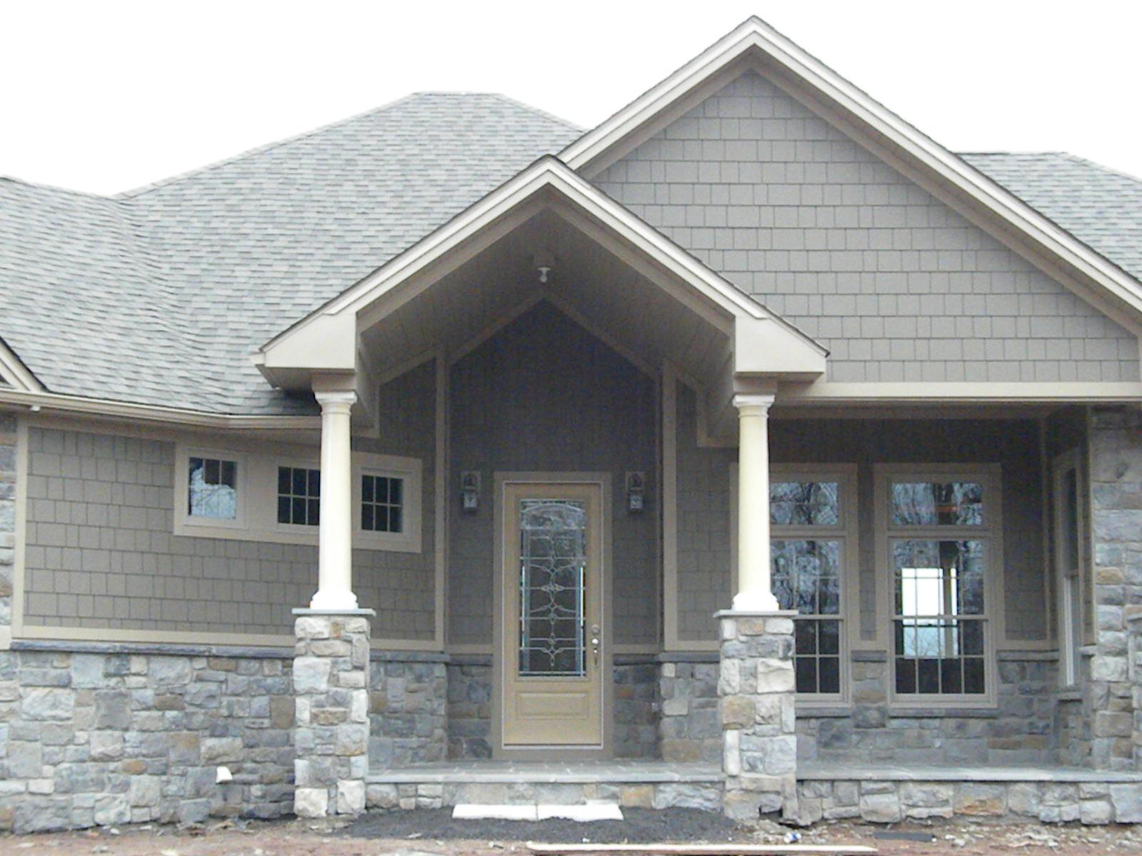 The entry front on, tapered columns on stone piers carrying the porch gable above a paneled door