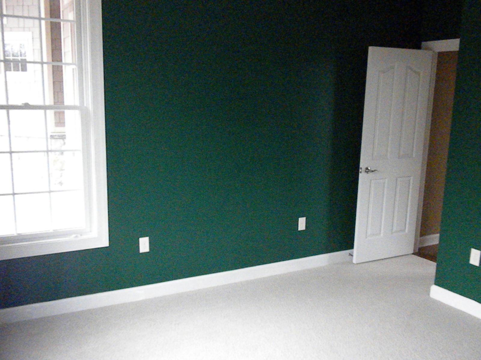 A room painted deep green, a white six-panel door standing open to the hall