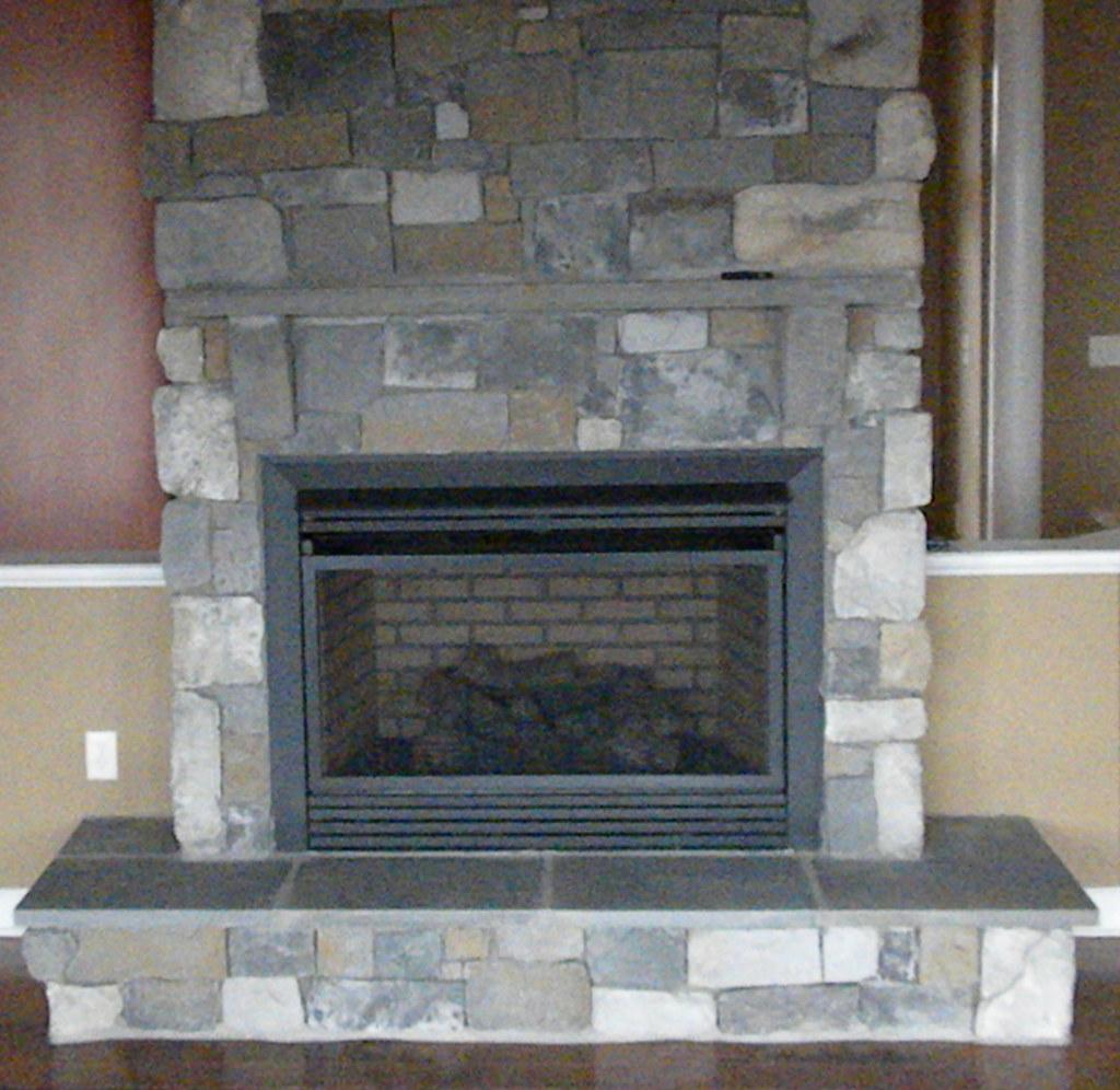 The fireplace close to, dressed stone running up to the ceiling above a black firebox and a slab hearth