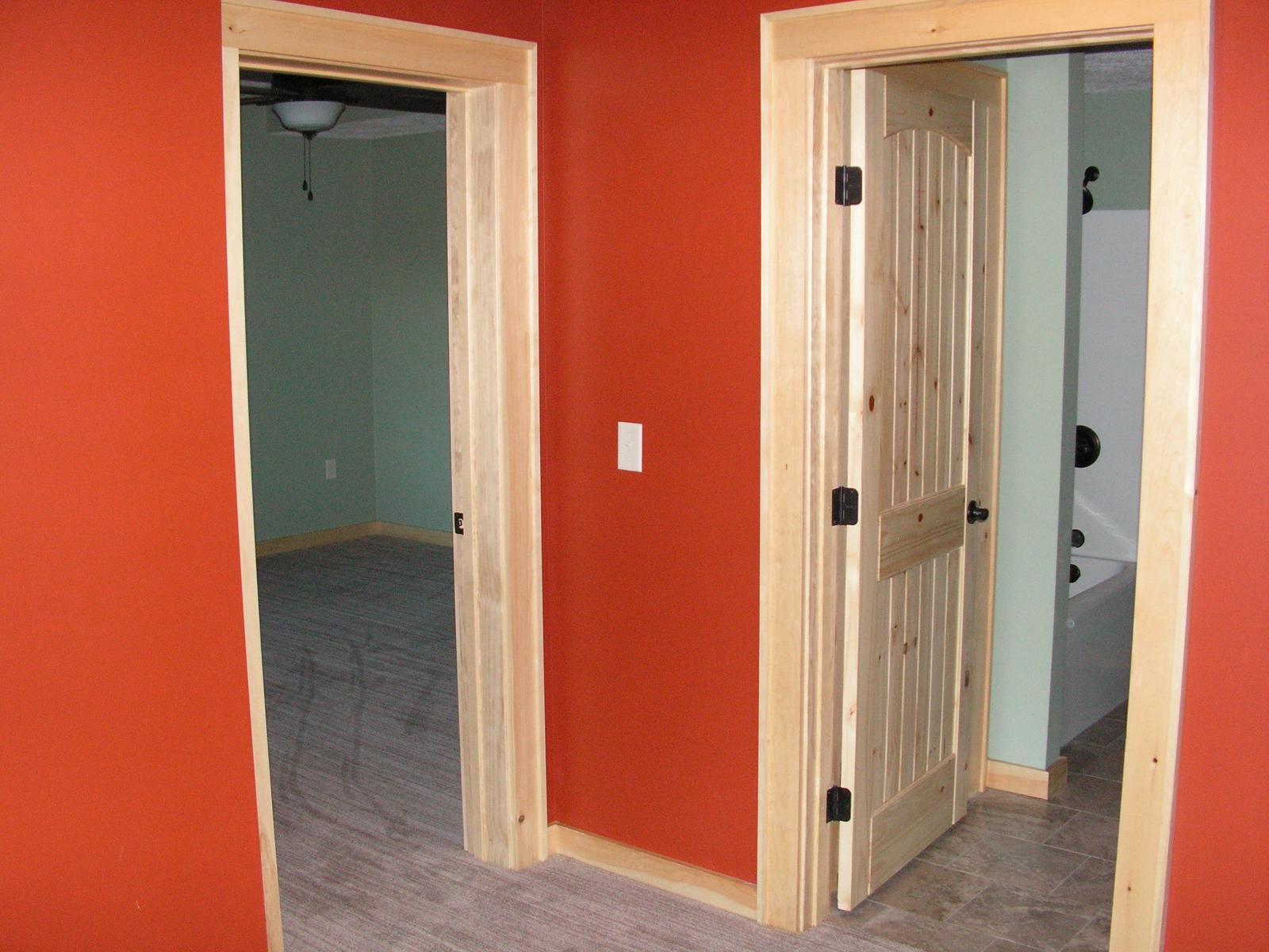 Two door openings side by side in a red wall, rooms beyond in bare finish