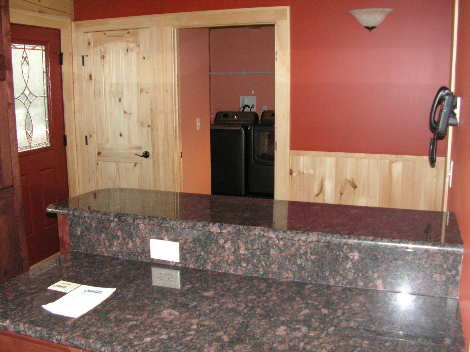 The island counter looking through to a laundry with a washer and dryer, red walls around the opening