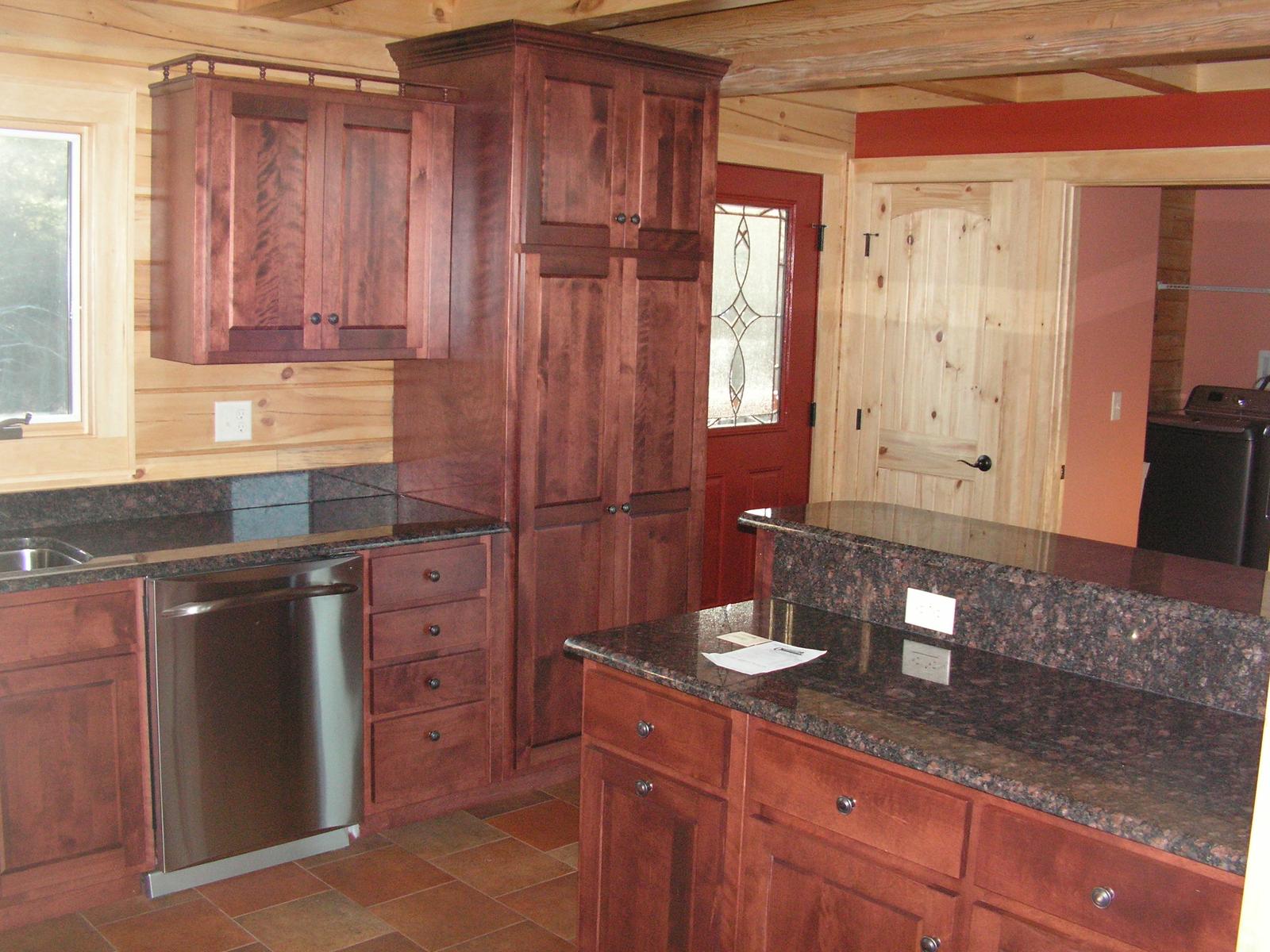 The kitchen island from the corner, cabinets to the ceiling and a leaded glass door beyond