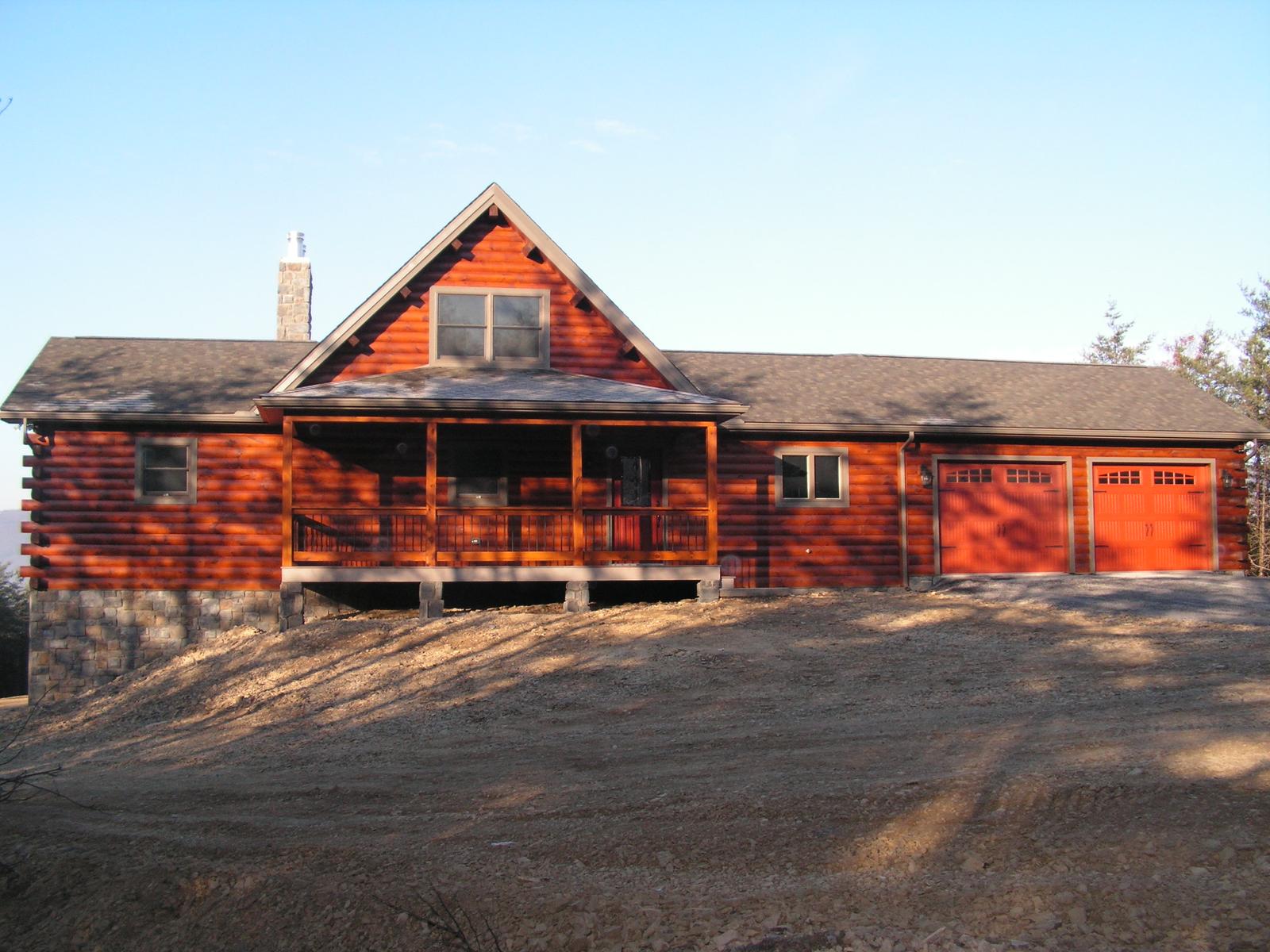 The same home square on in low sun, porch running the length of it and two garage doors at the end