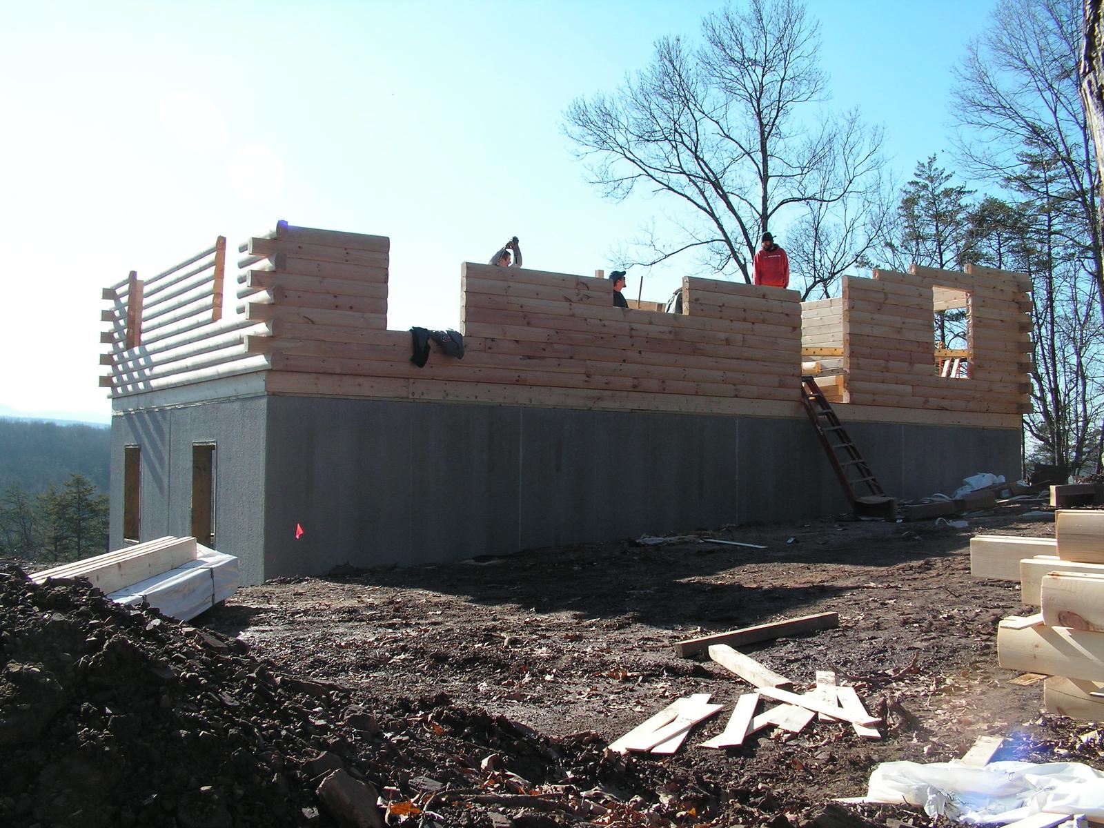 The gable end going up, upper courses stepped and stacked and a worker on the wall
