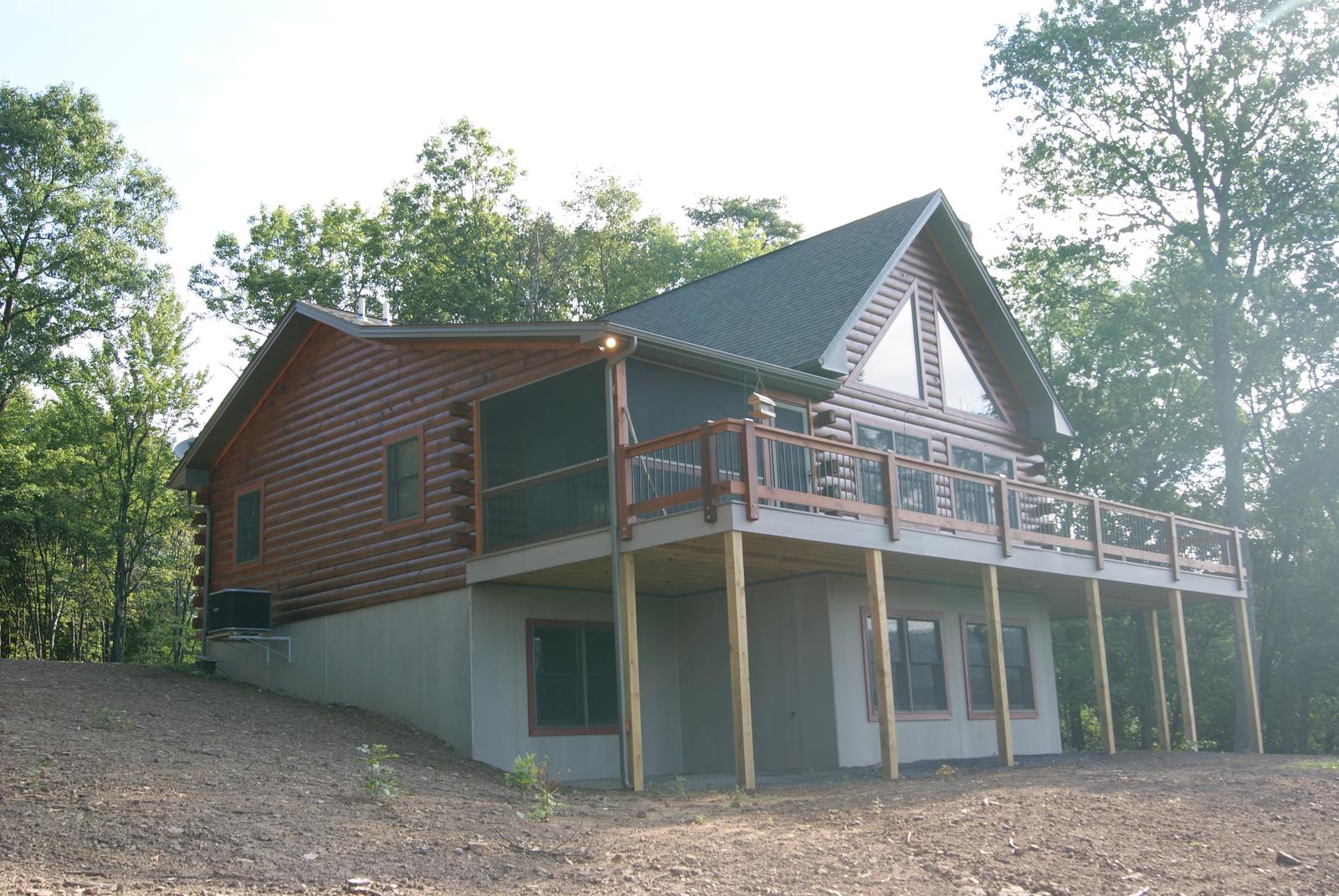 The home from the low side, walkout level under the deck and bare graded ground all around