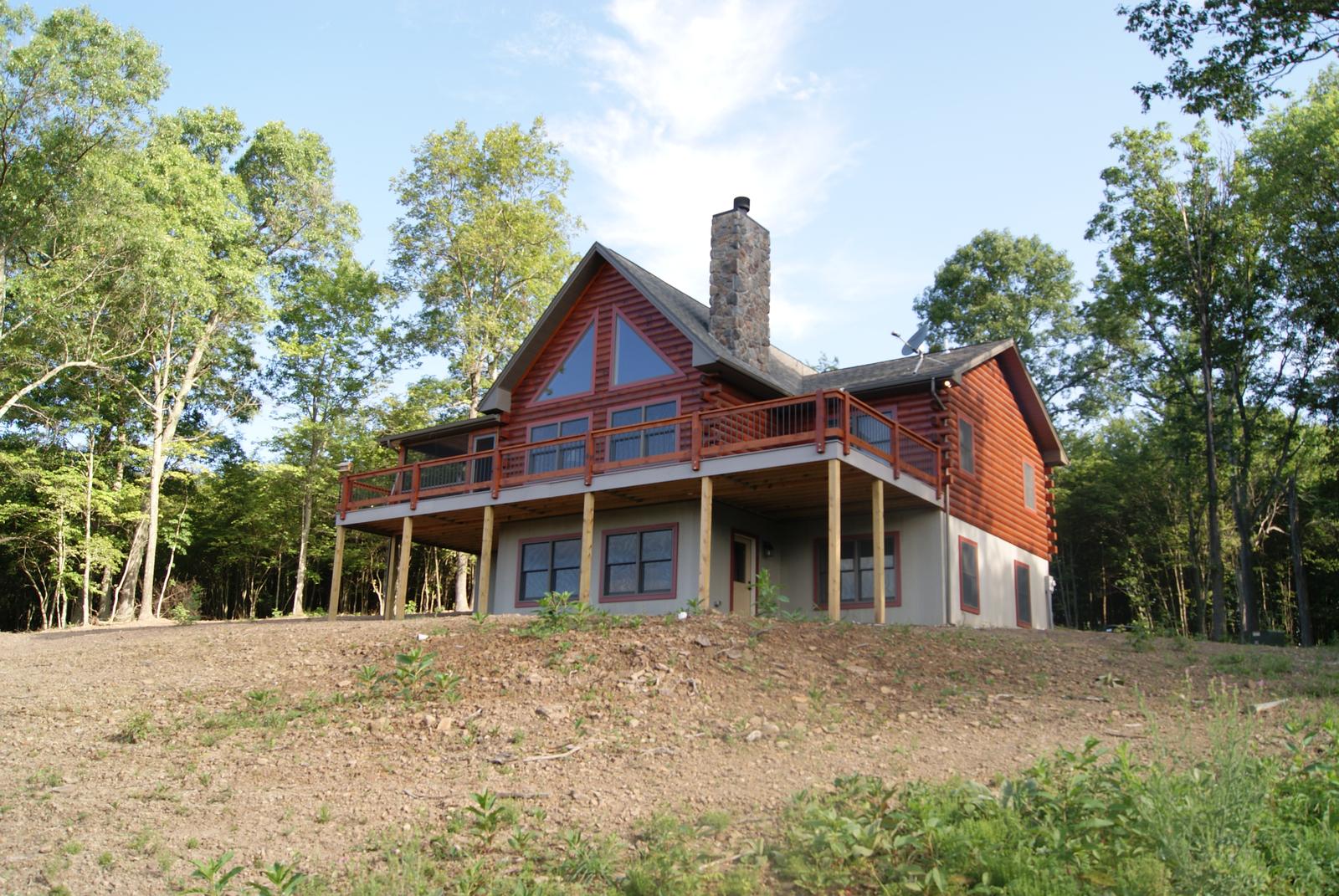 The home square on across rough ground, gable glass centered over a full-width deck on posts