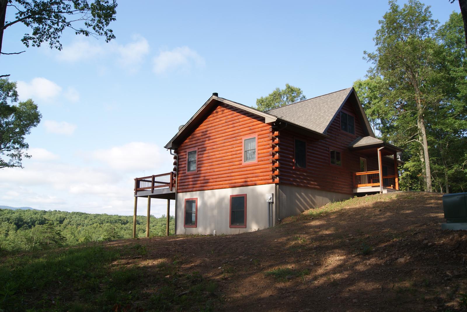 The home from the open hillside, deck along the near side and the ground falling away to a distant valley