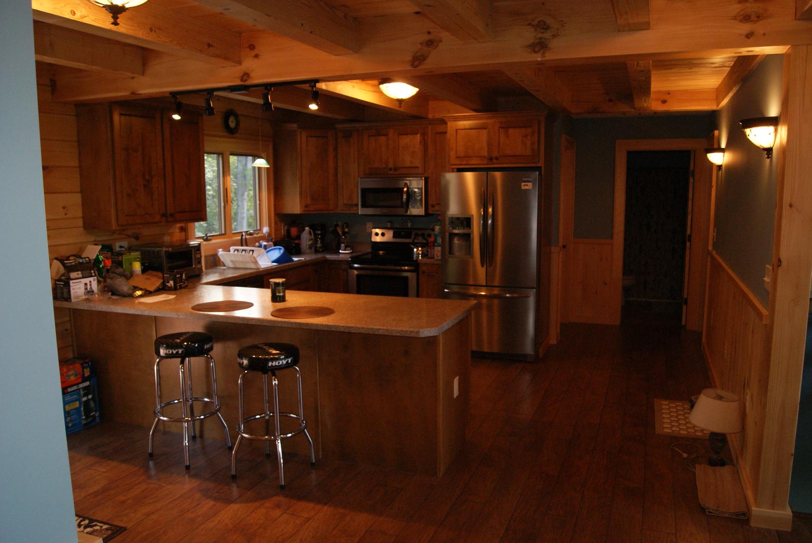 The kitchen from the far side, stainless range and refrigerator along the run and a doorway beyond
