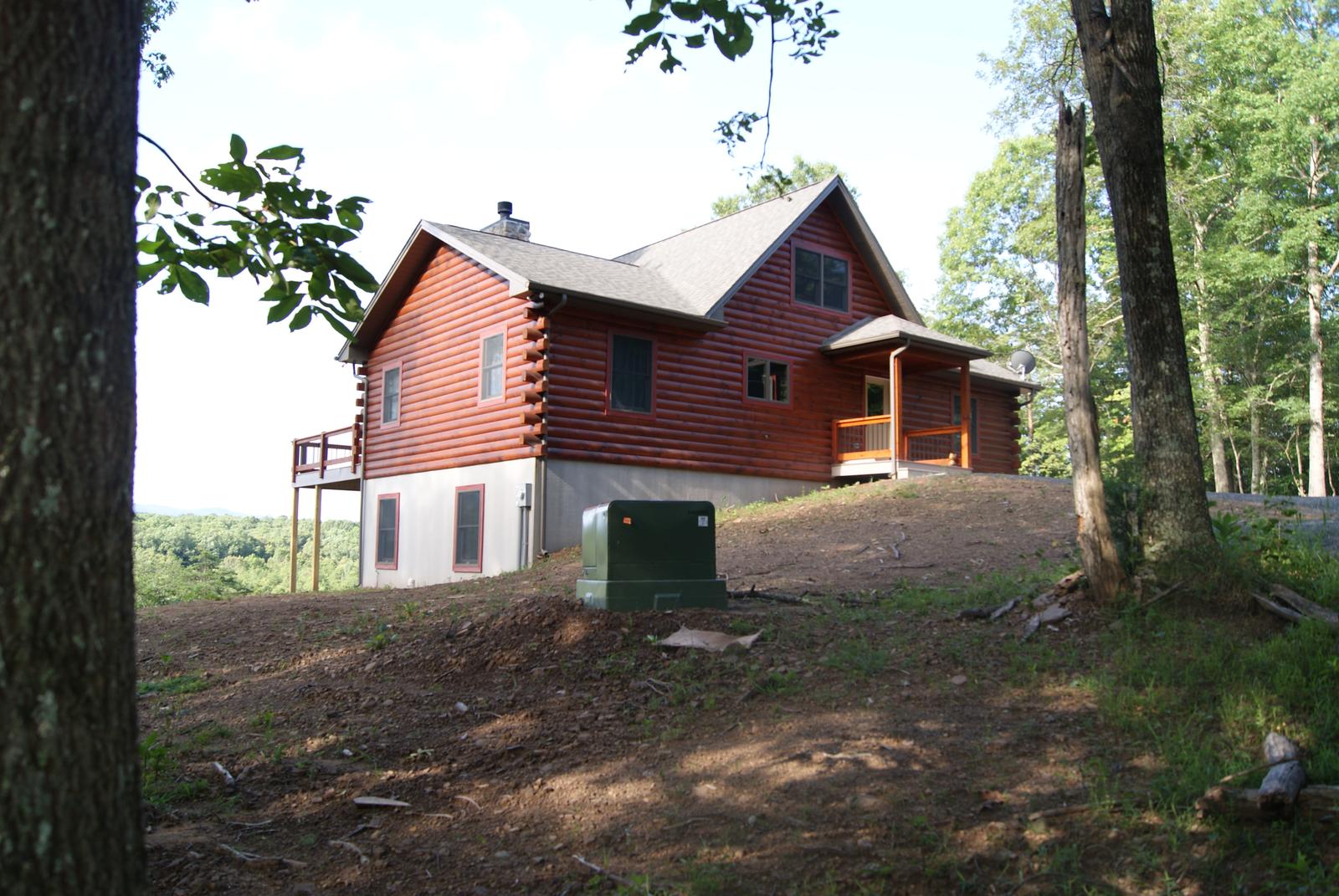 The home from below the bank, its railed deck standing on posts above a walkout level