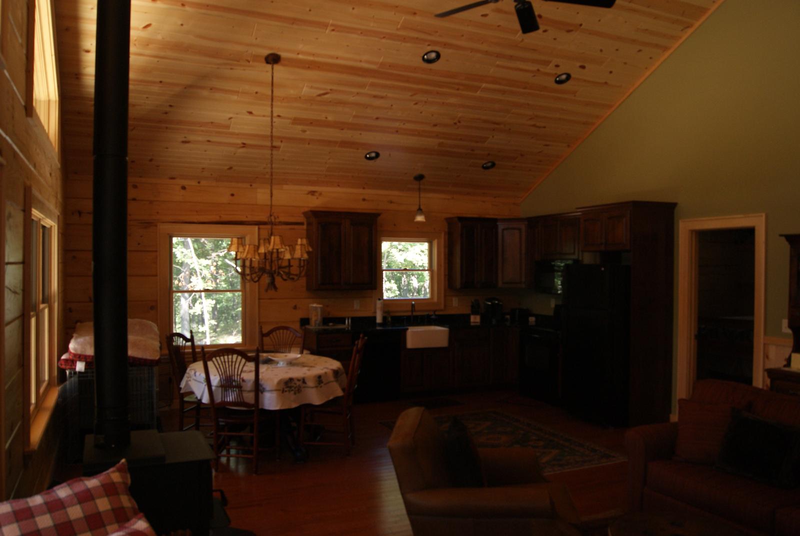 The room toward the kitchen, chandelier over a dining table and cabinets along the far wall