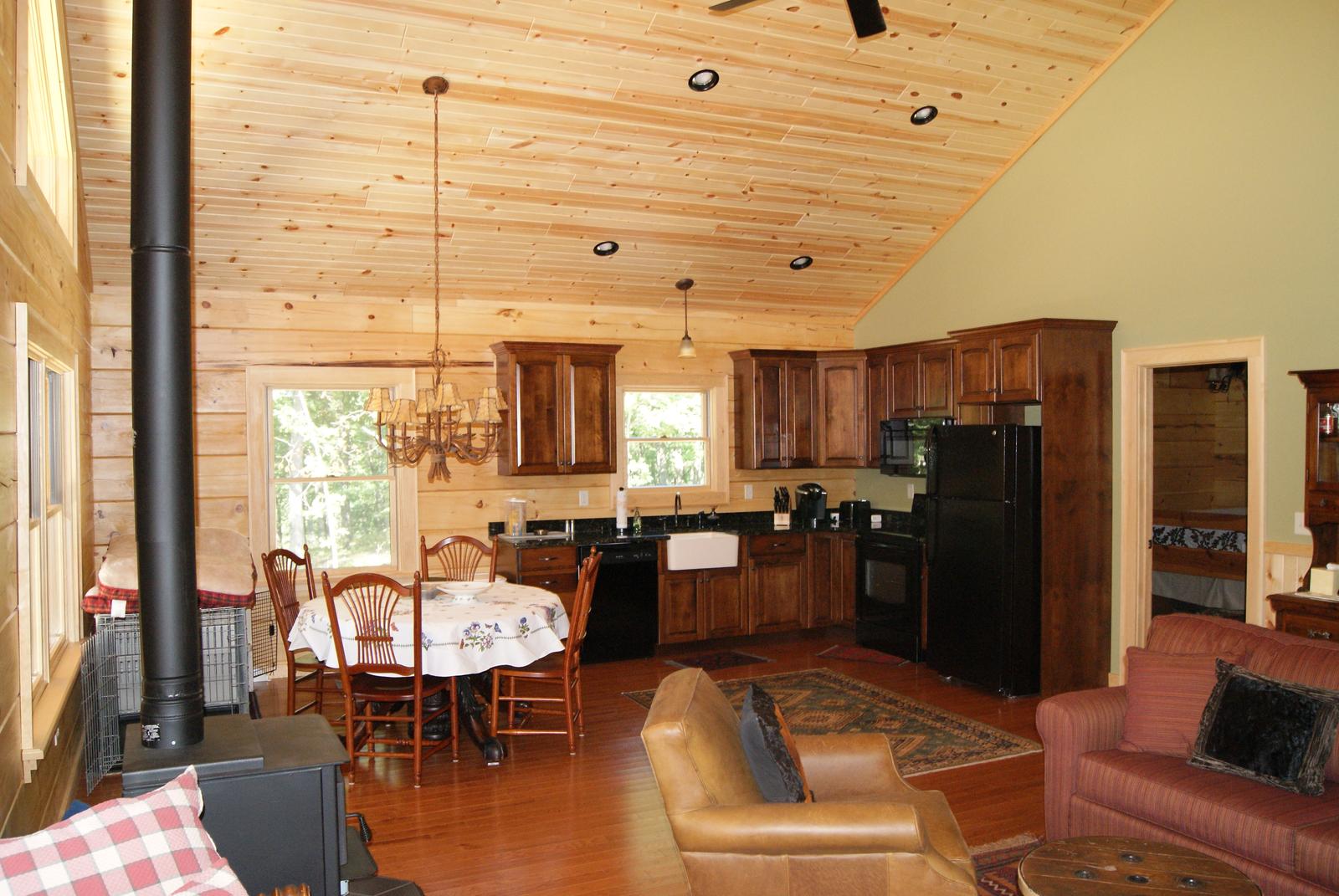 The kitchen from the seating area, black appliances and wood cabinets under the sloped ceiling